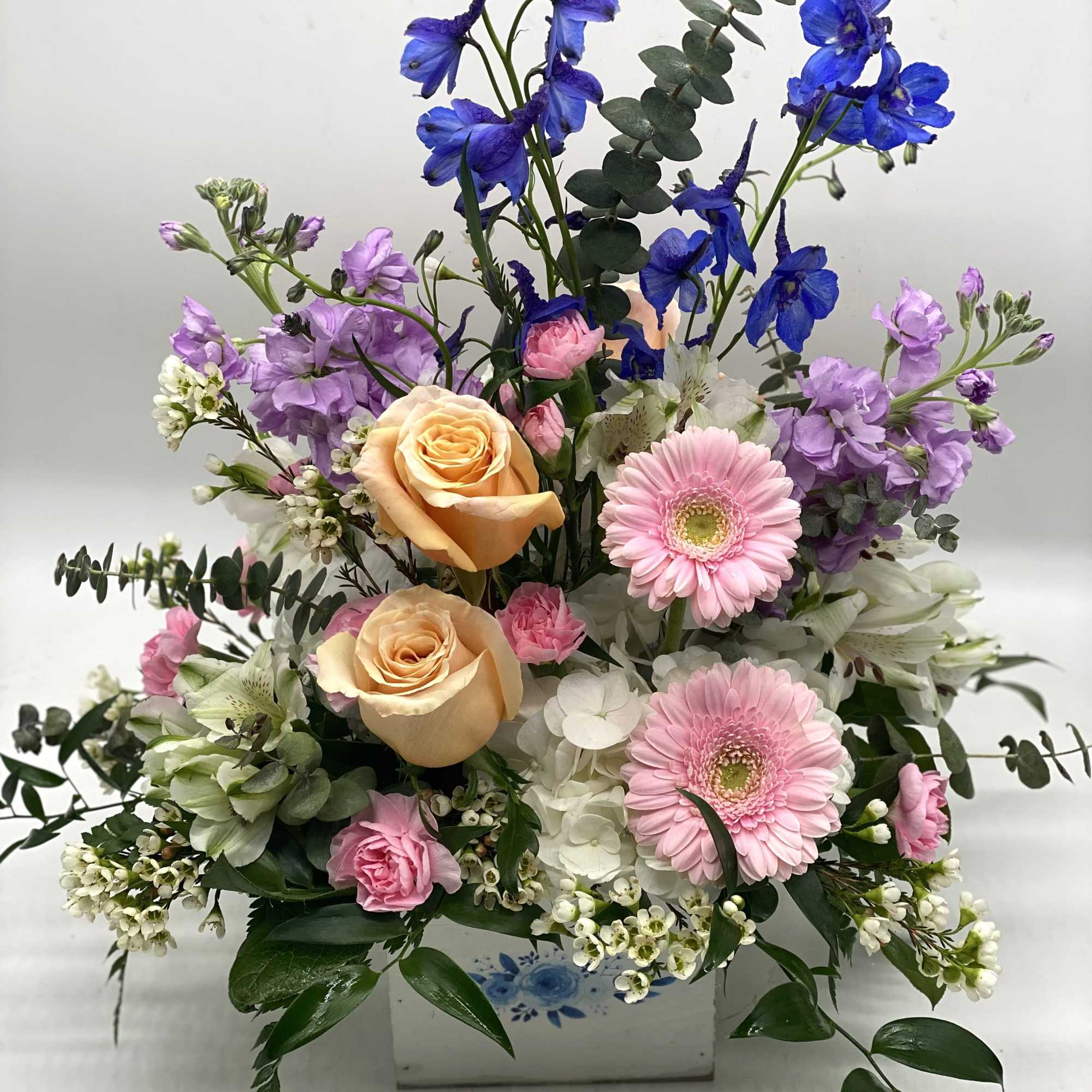 A soft pastel blend of fresh flowers designed in a white wooden