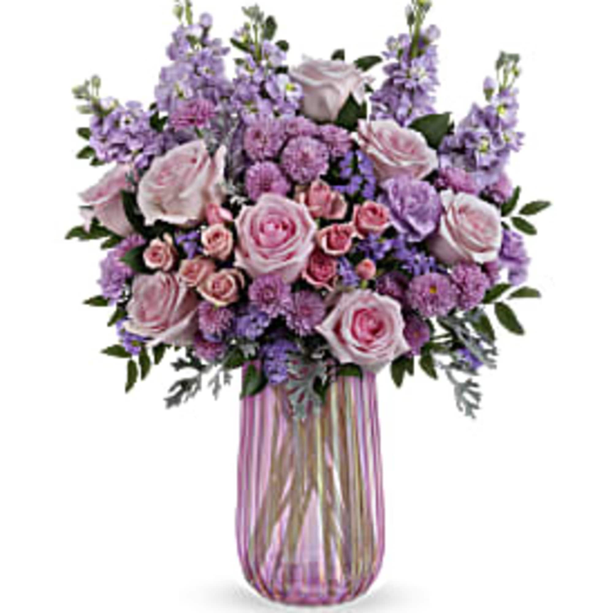 PURPLE, LAVENDER, PINK, AND CREME ROSES IN A TALL, CLEAR/PINK VASE