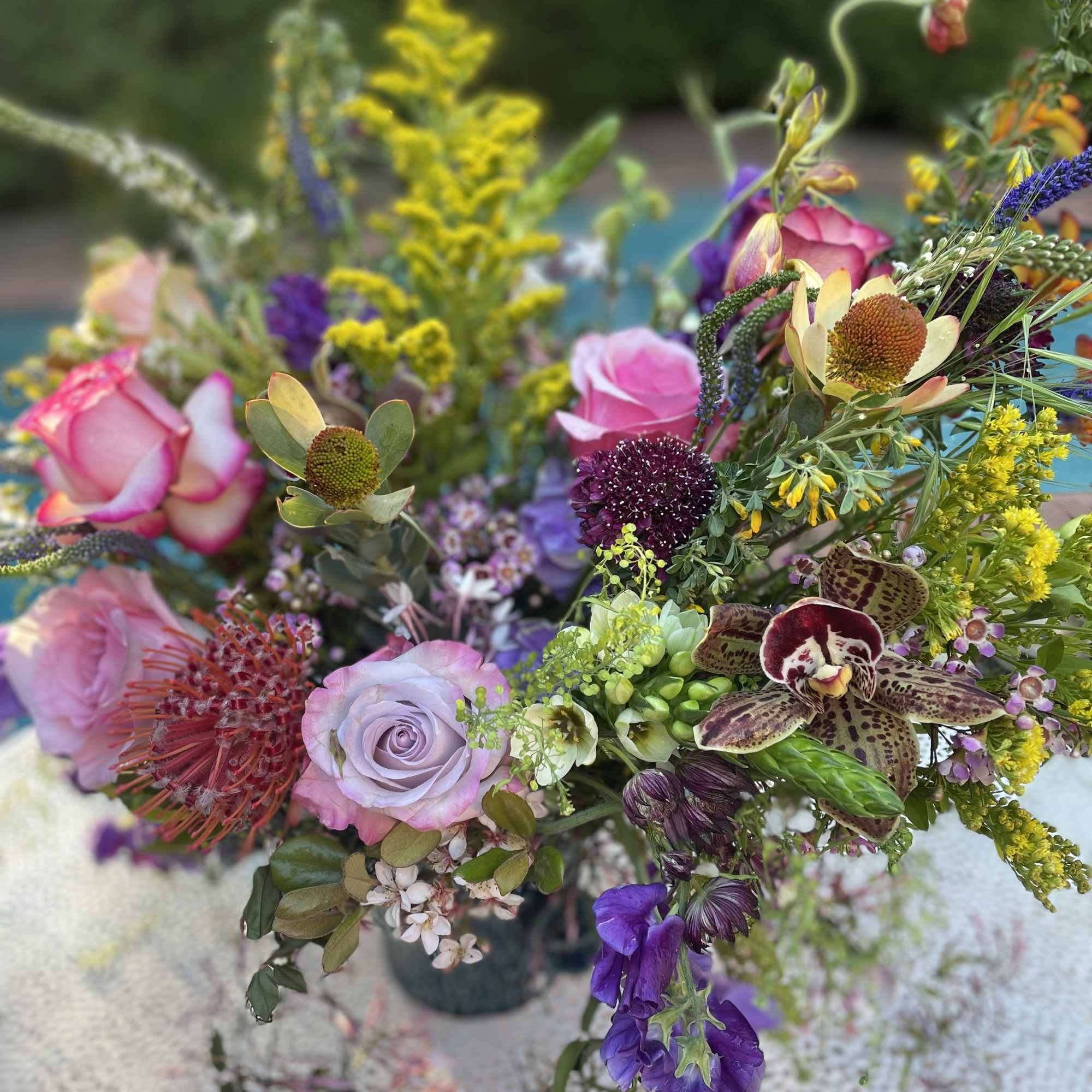 Roses, sweet peas, orchids, and jasmine make this arrangement fragrant and beautiful.