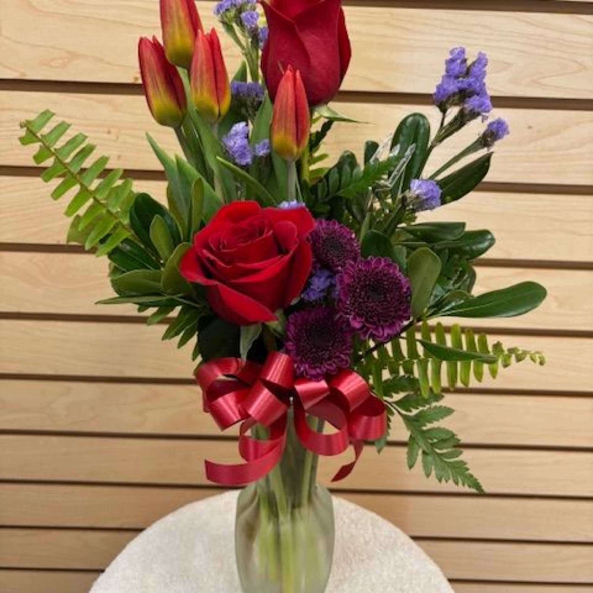 Mixed cut arrangement with red roses, orange tulips, purple buttons, lavender statice