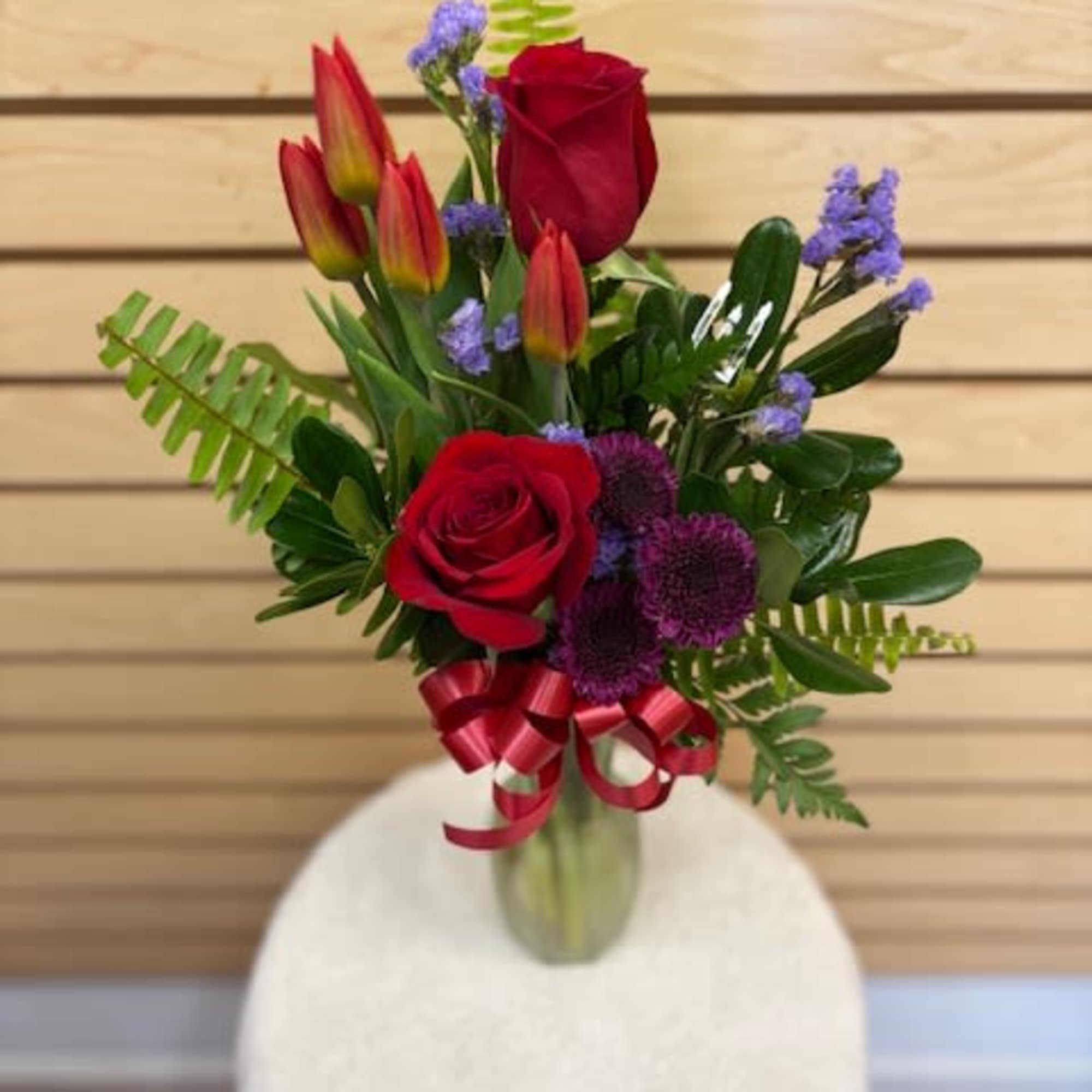 Mixed cut arrangement with red roses, orange tulips, purple buttons, lavender statice