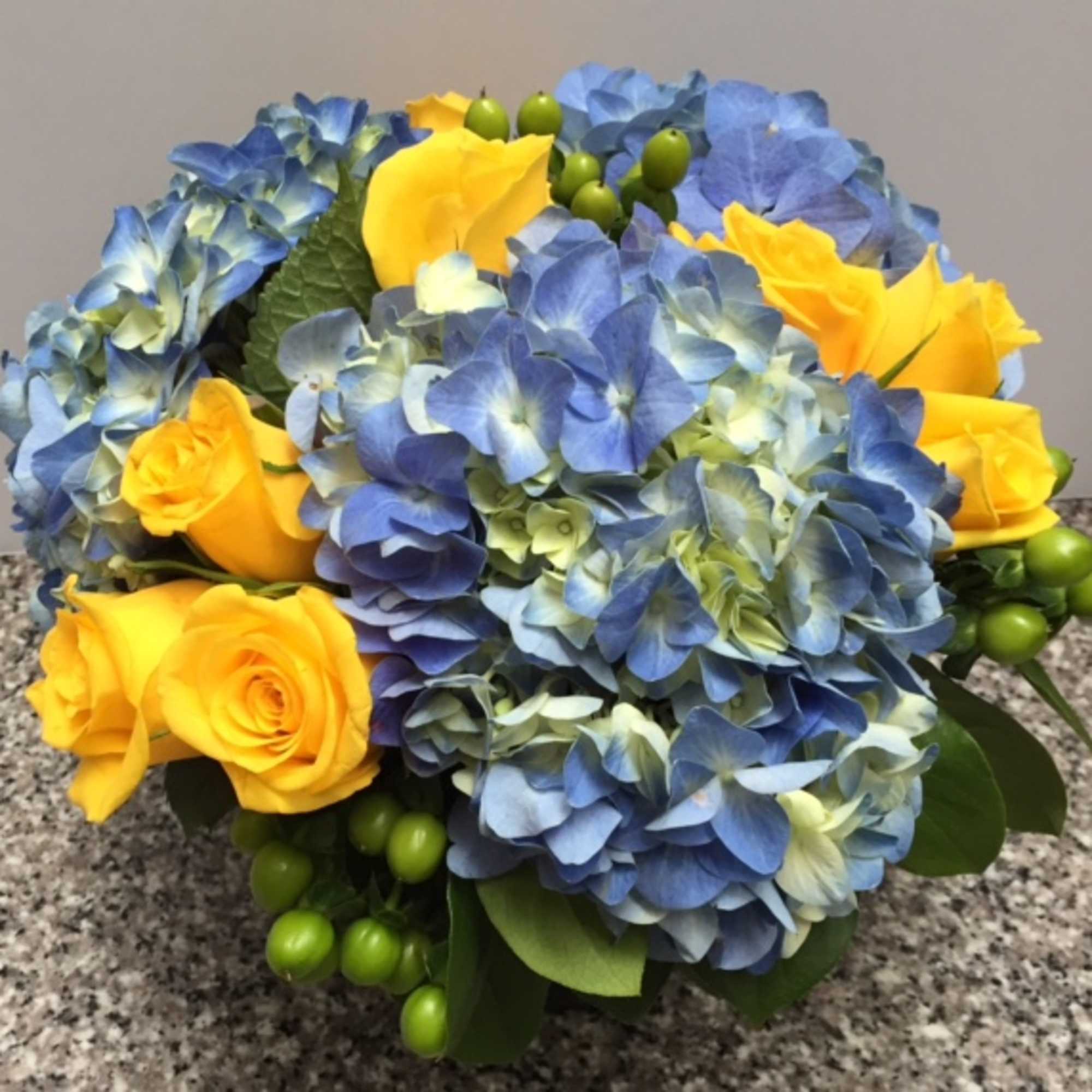 A classic combination of blue hydrangea with yellow roses. Arrangement arrives in