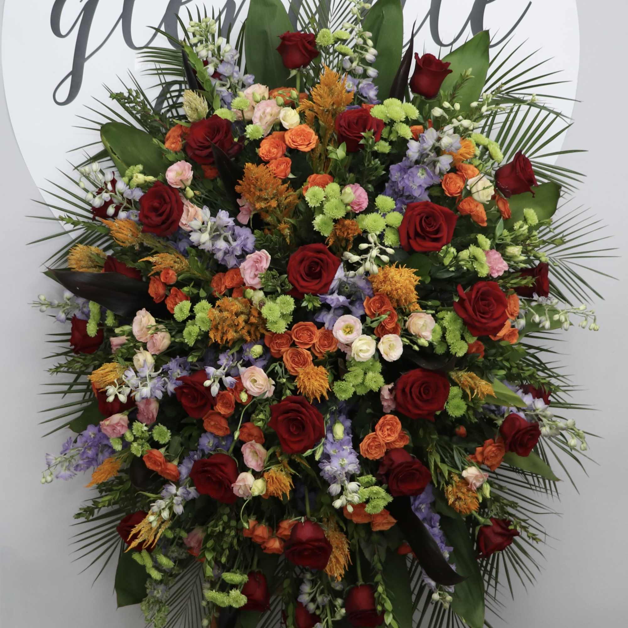 With bright multi-toned roses, snapdragons and seasonal greens, this sympathy arrangement stands