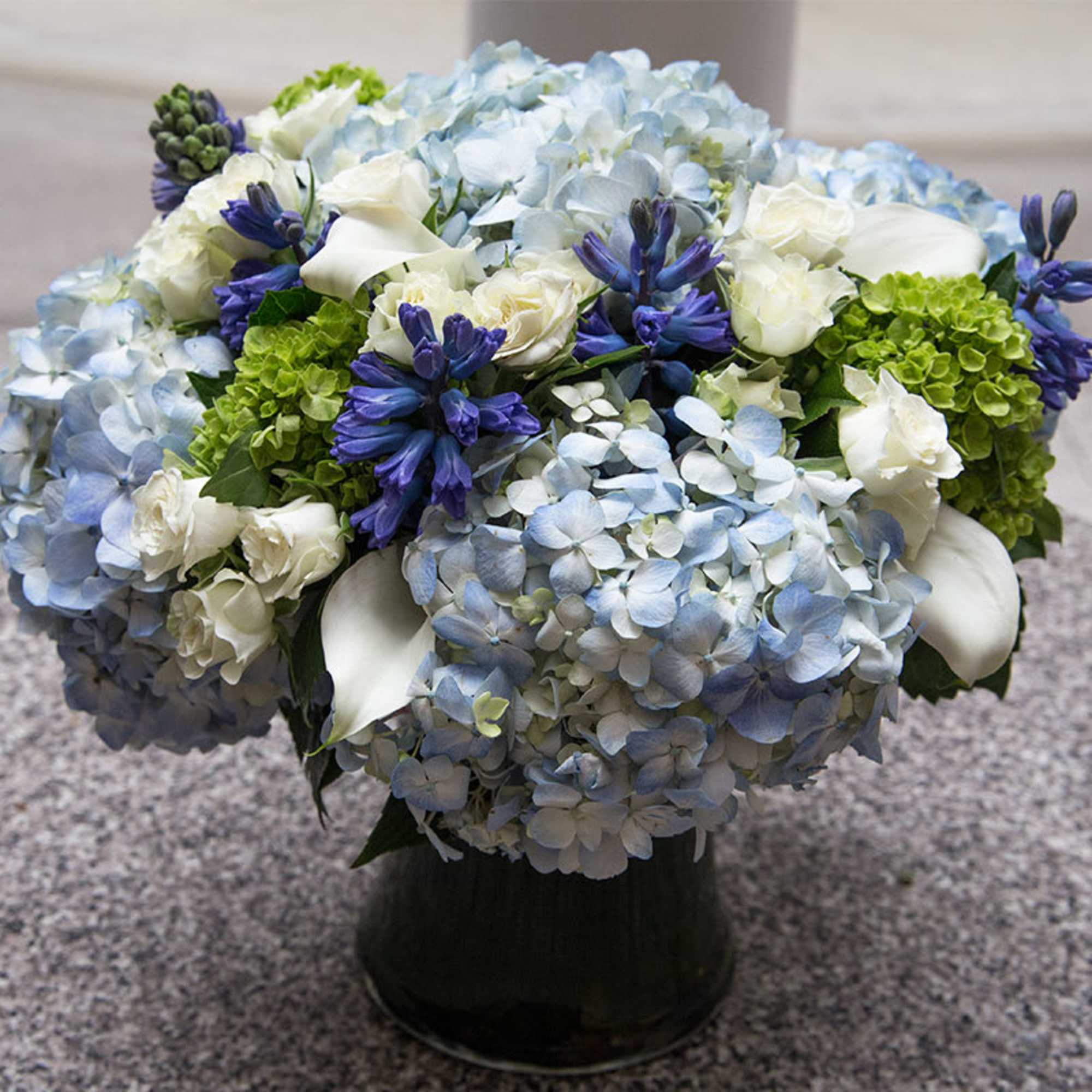 This white and blue arrangement includes blue hydrangea, blue hyacinth, green hydrangea This white and blue arrangement includes blue hydrangea, blue hyacinth, green hydrangea
