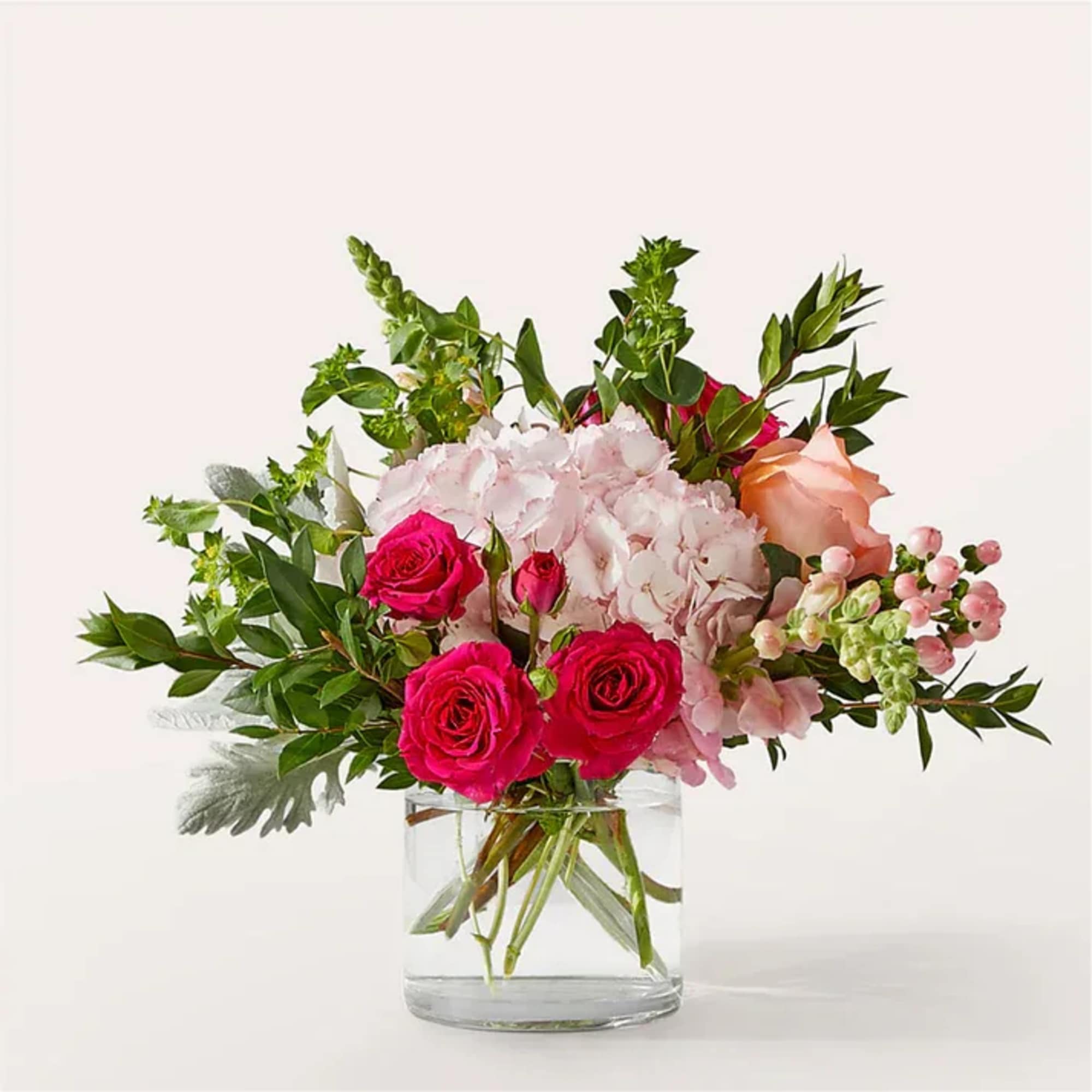 Blush hydrangea, pink snapdragons, and coral roses are beautifully arranged by a