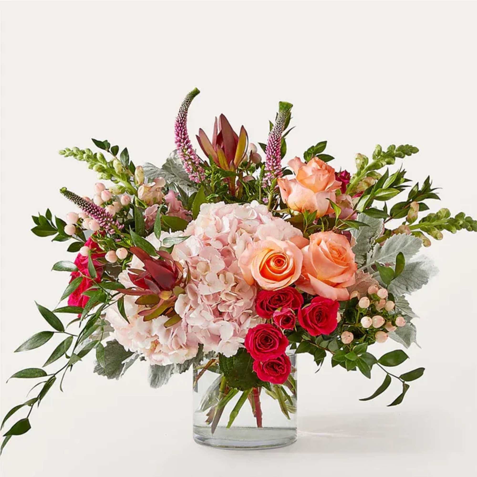 Blush hydrangea, pink snapdragons, and coral roses are beautifully arranged by a