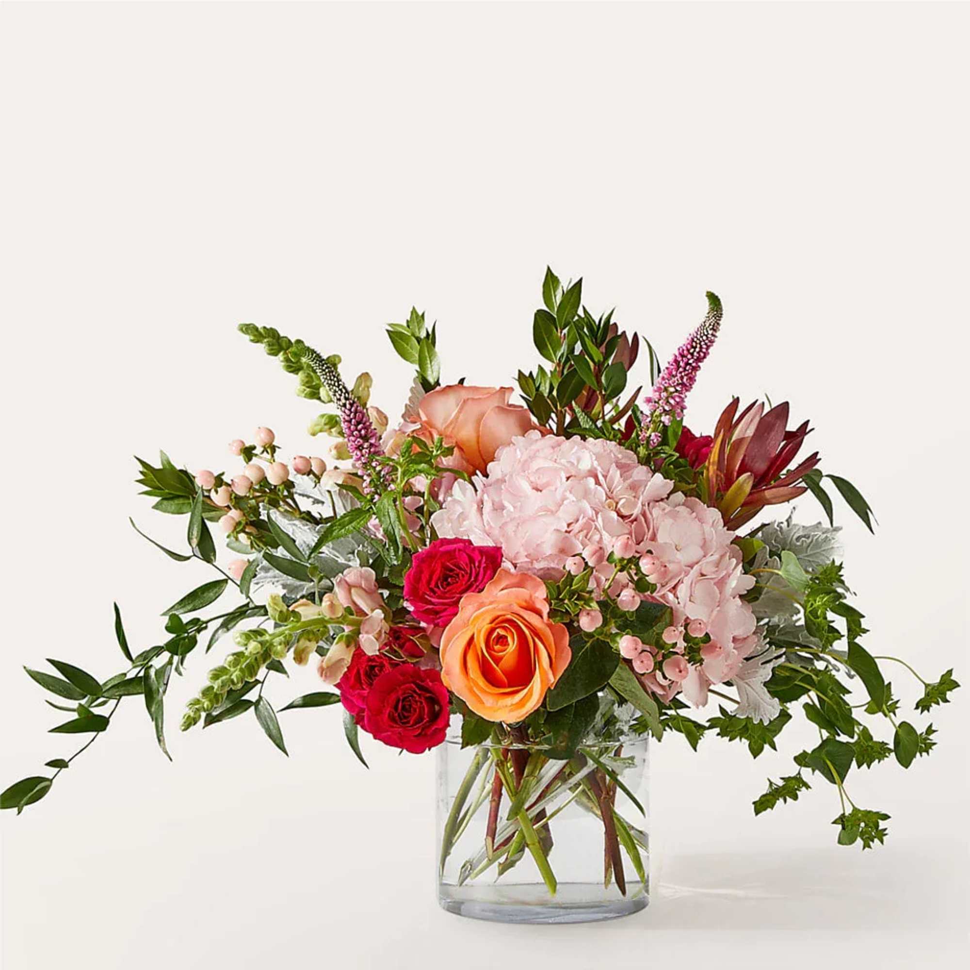 Blush hydrangea, pink snapdragons, and coral roses are beautifully arranged by a