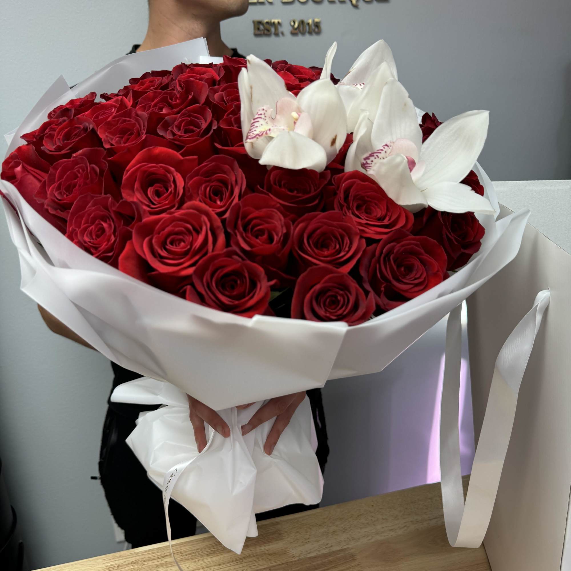 50 Premium Long-stem roses with cymbidium orchids in our signature wrap. All