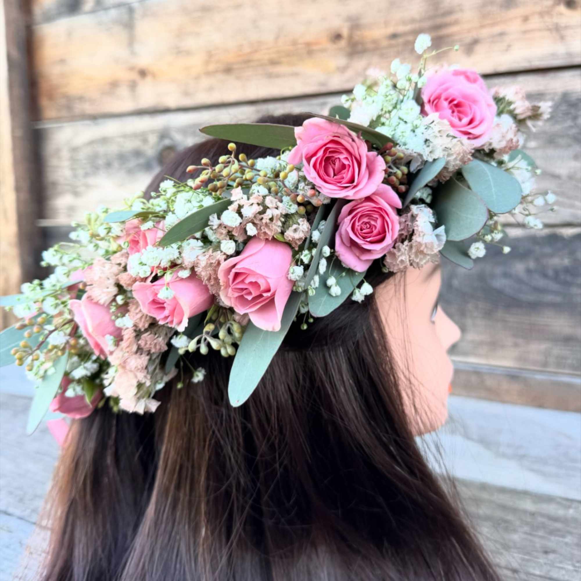 A  floral crown featuring soft pink roses, baby&#039;s breath, and eucalyptus
