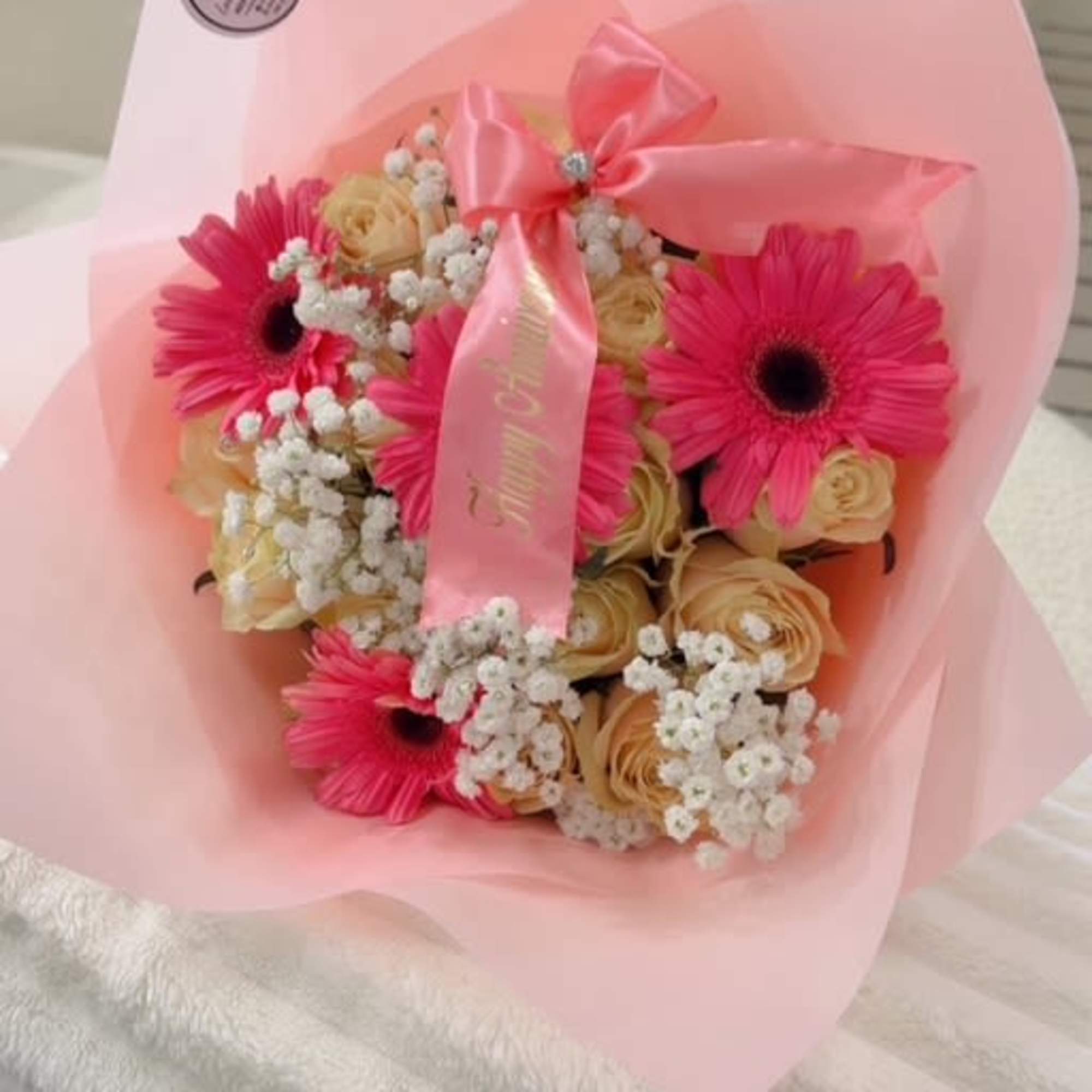 A charming blend of hot pink gerberas, soft blush roses, and delicate A charming blend of hot pink gerberas, soft blush roses, and delicate
