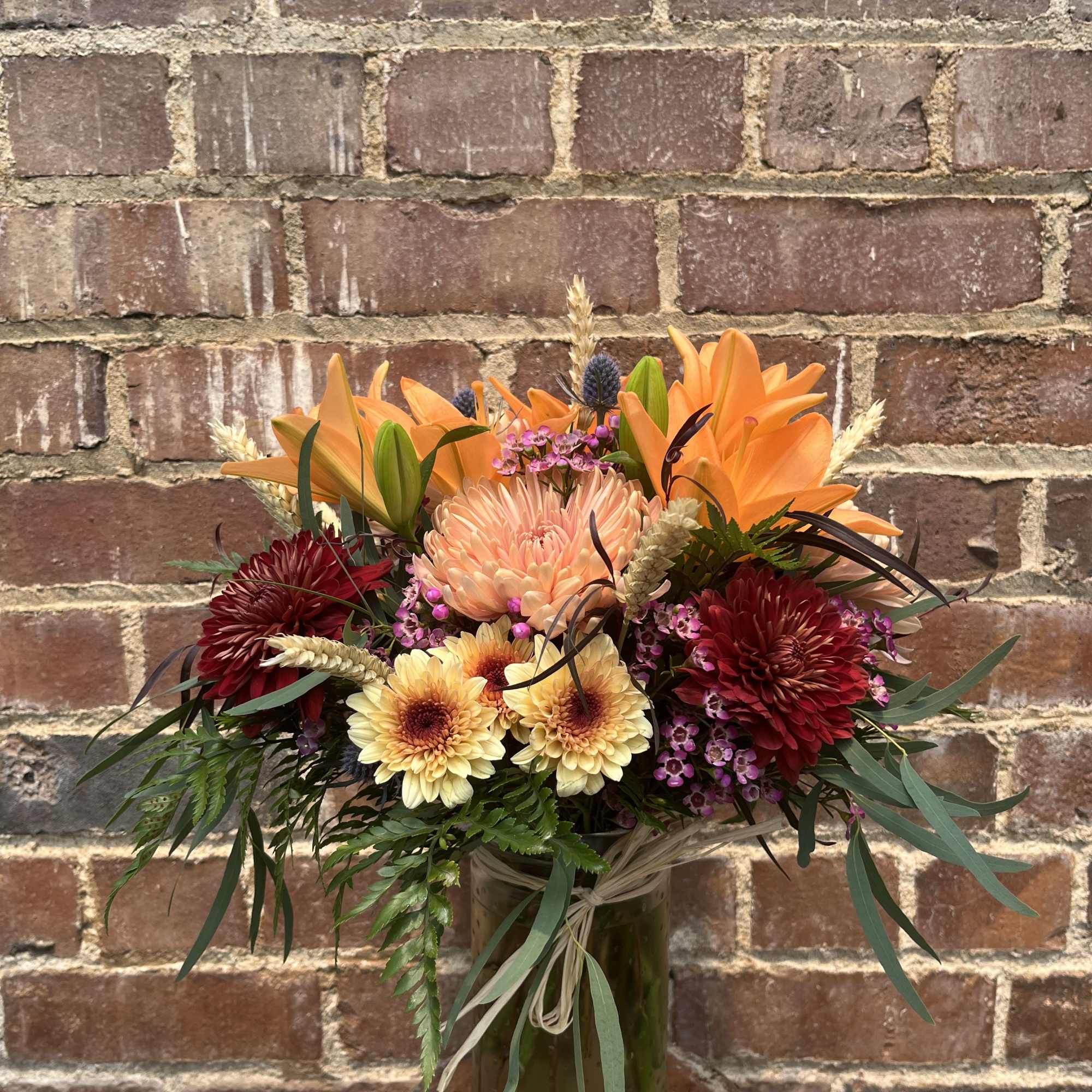 Lilies, chrysanthemums, thistle, accent flowers, dried wheat, and assorted greenery. Arranged in Lilies, chrysanthemums, thistle, accent flowers, dried wheat, and assorted greenery. Arranged in