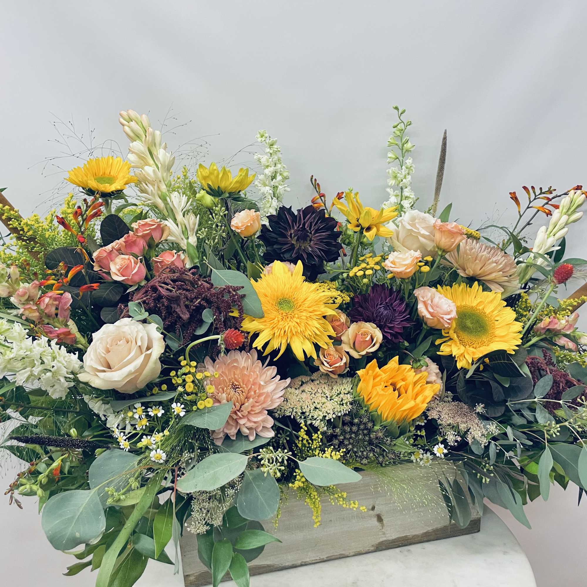 Moody autumnal palette of mixed blooms including sunflowers, roses, snapdragons, ranunculus, seasonal