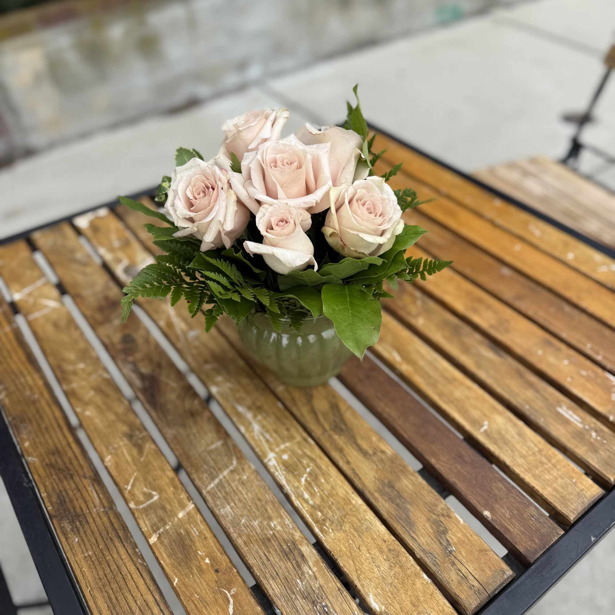 Six quicksand roses arranged in a vase with foliage for pick up.