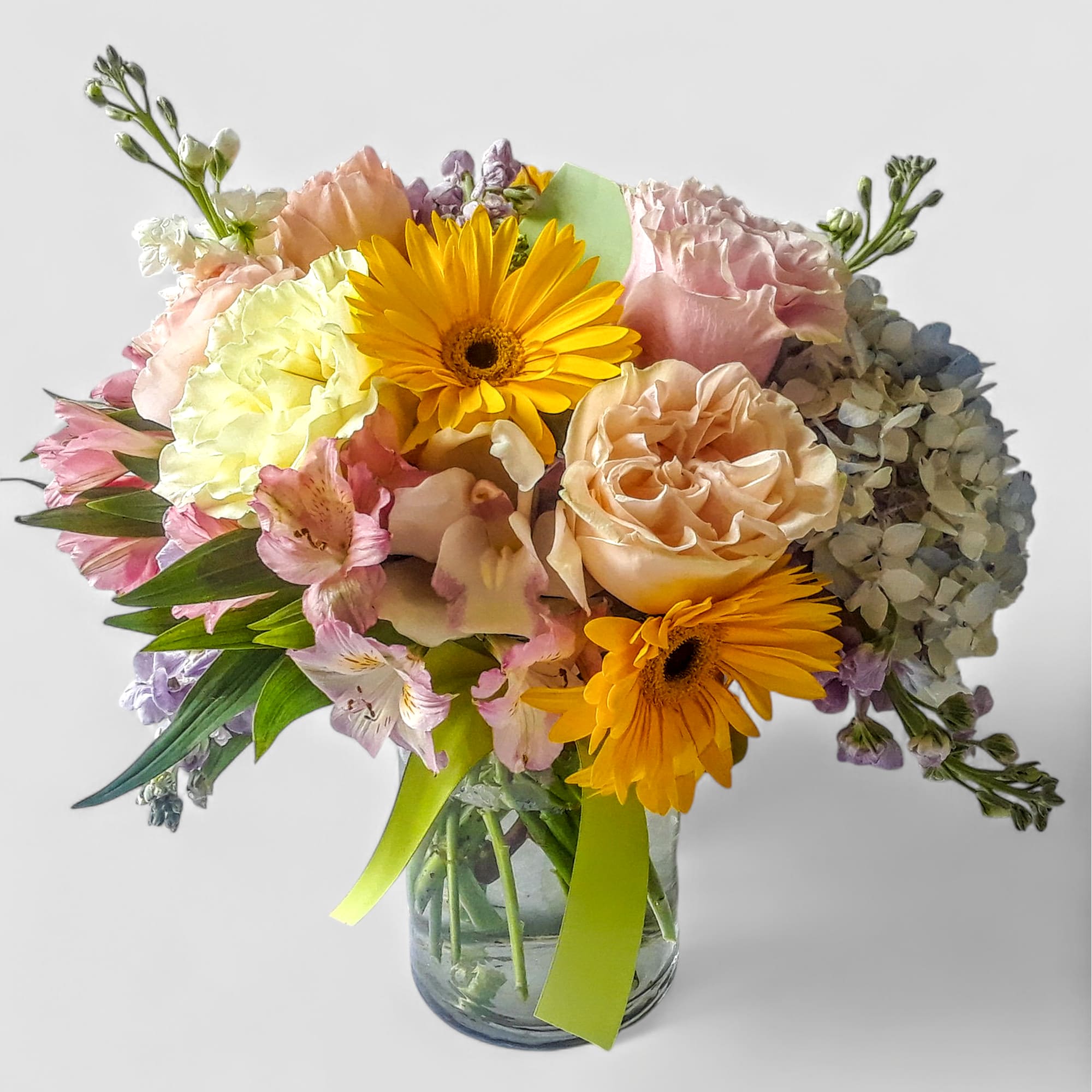 Roses orchids  and more arranged in a tall modern glass cylinder