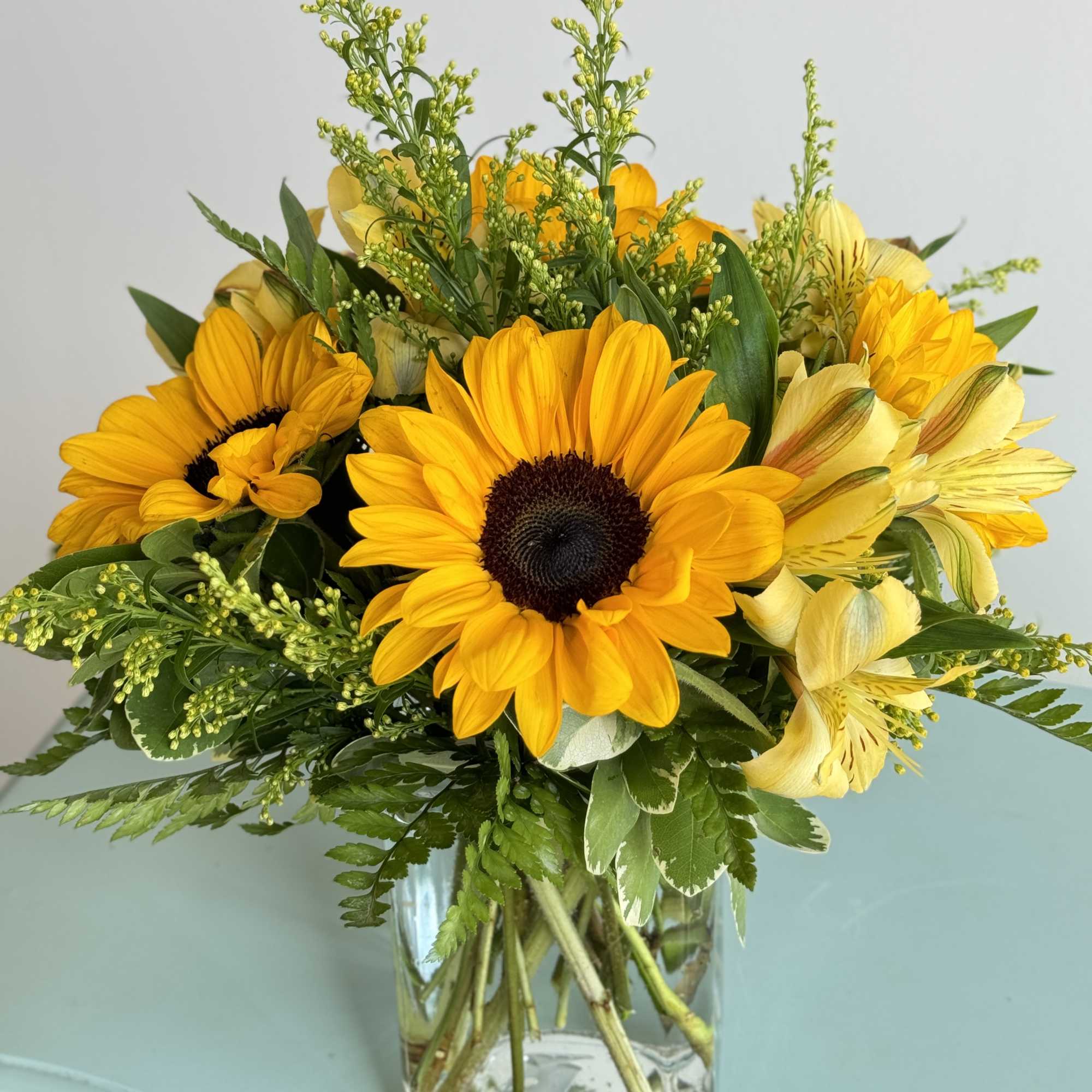 Brighten someone’s day with bright yellow sunflowers accented with solidago and arranged Brighten someone’s day with bright yellow sunflowers accented with solidago and arranged