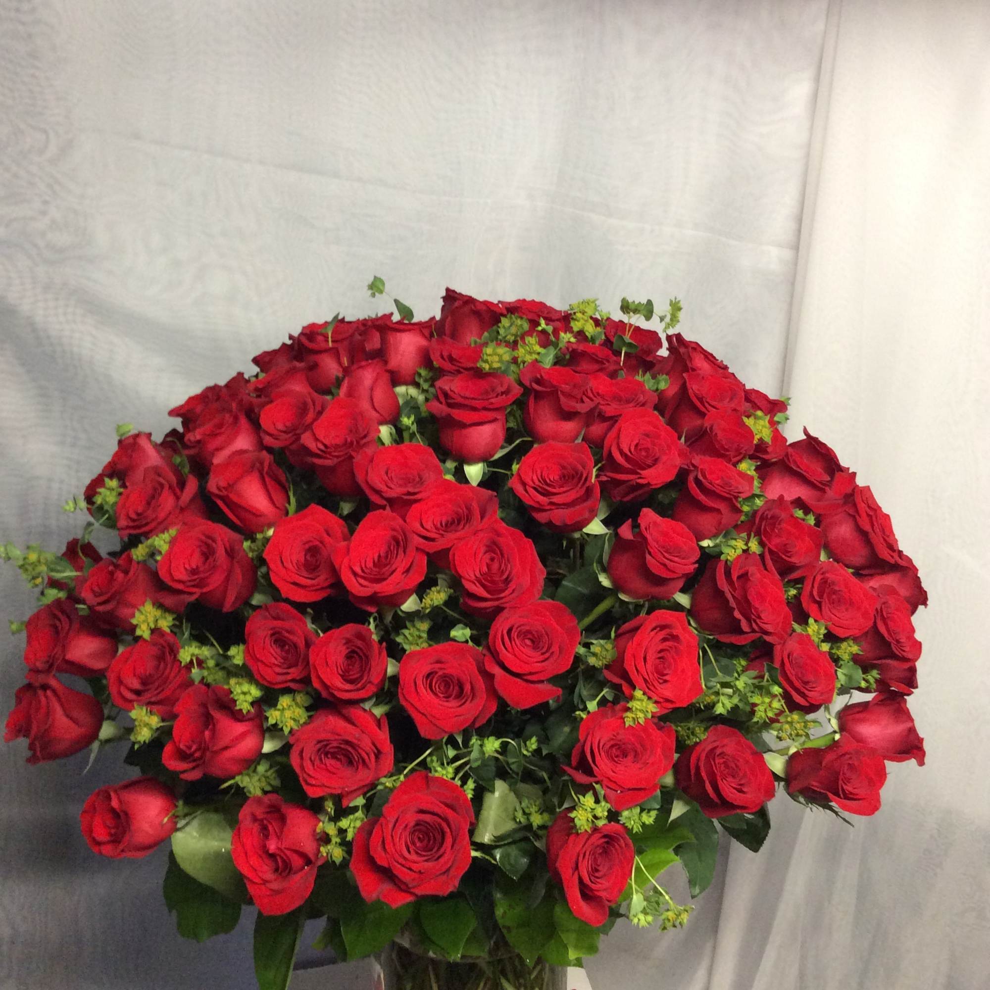 Beautiful flower arrangement with 100 red roses in cylinder vase 