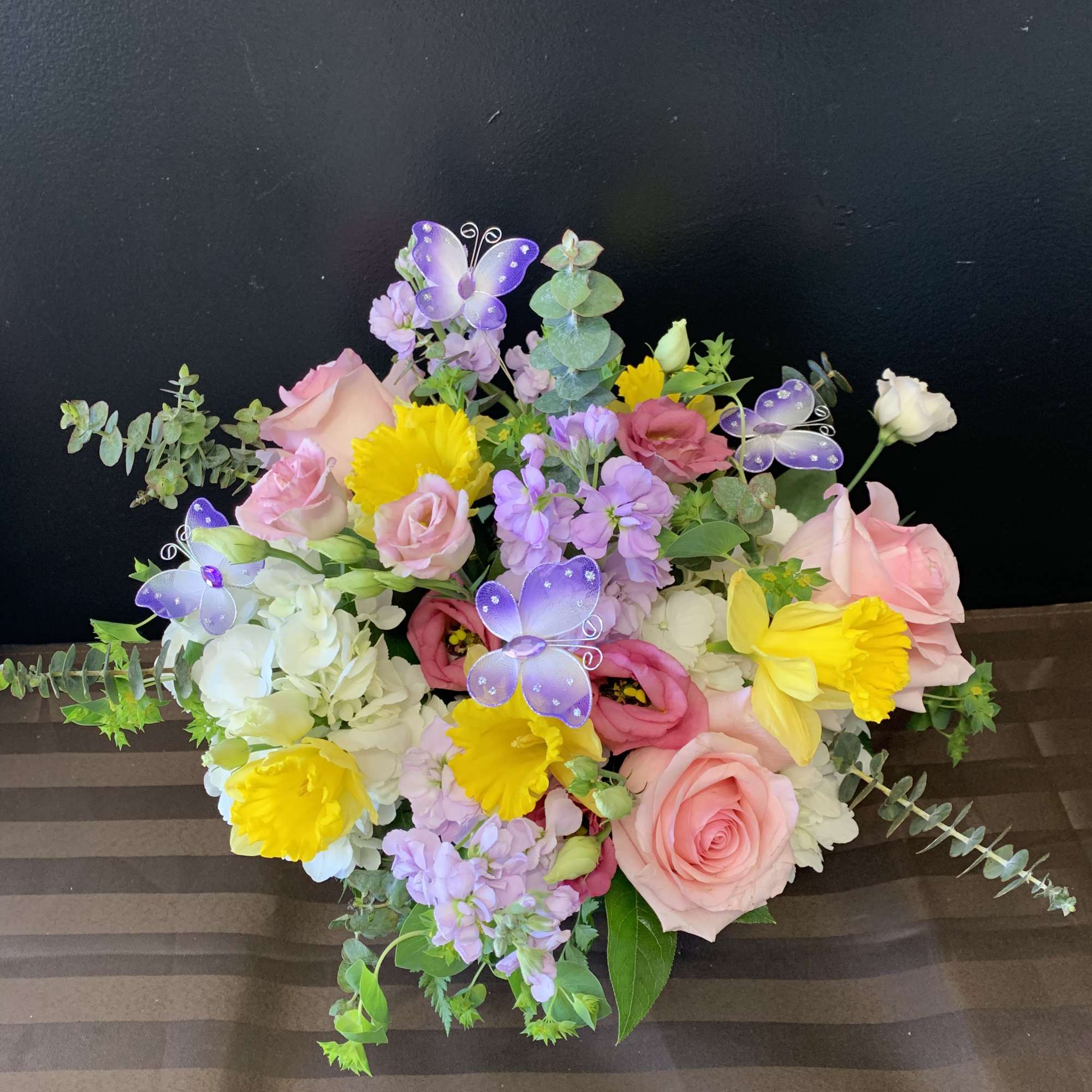 A beautiful flower arrangement with butterflies, white hydrangea, daffodils, eucalyptus, roses, stock