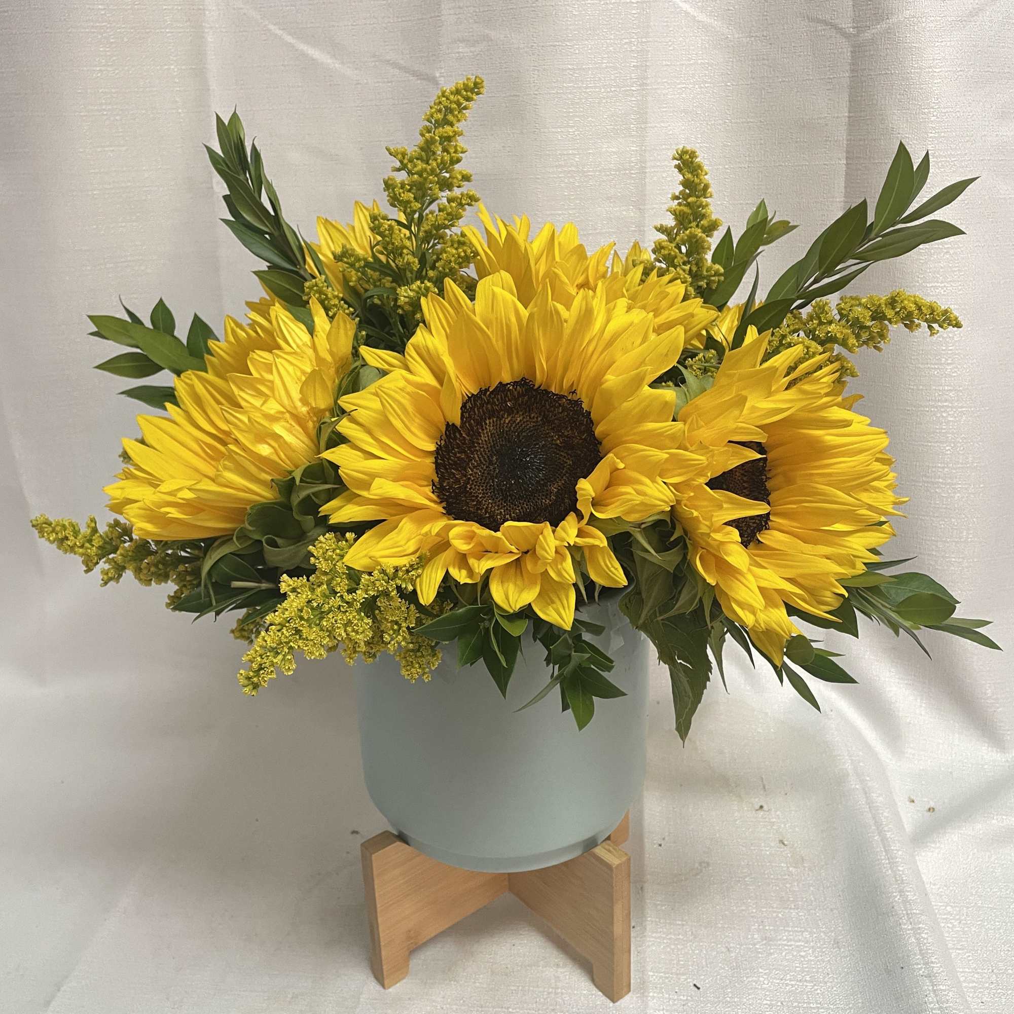 A beautiful array of sunflowers in a modern light blue container.