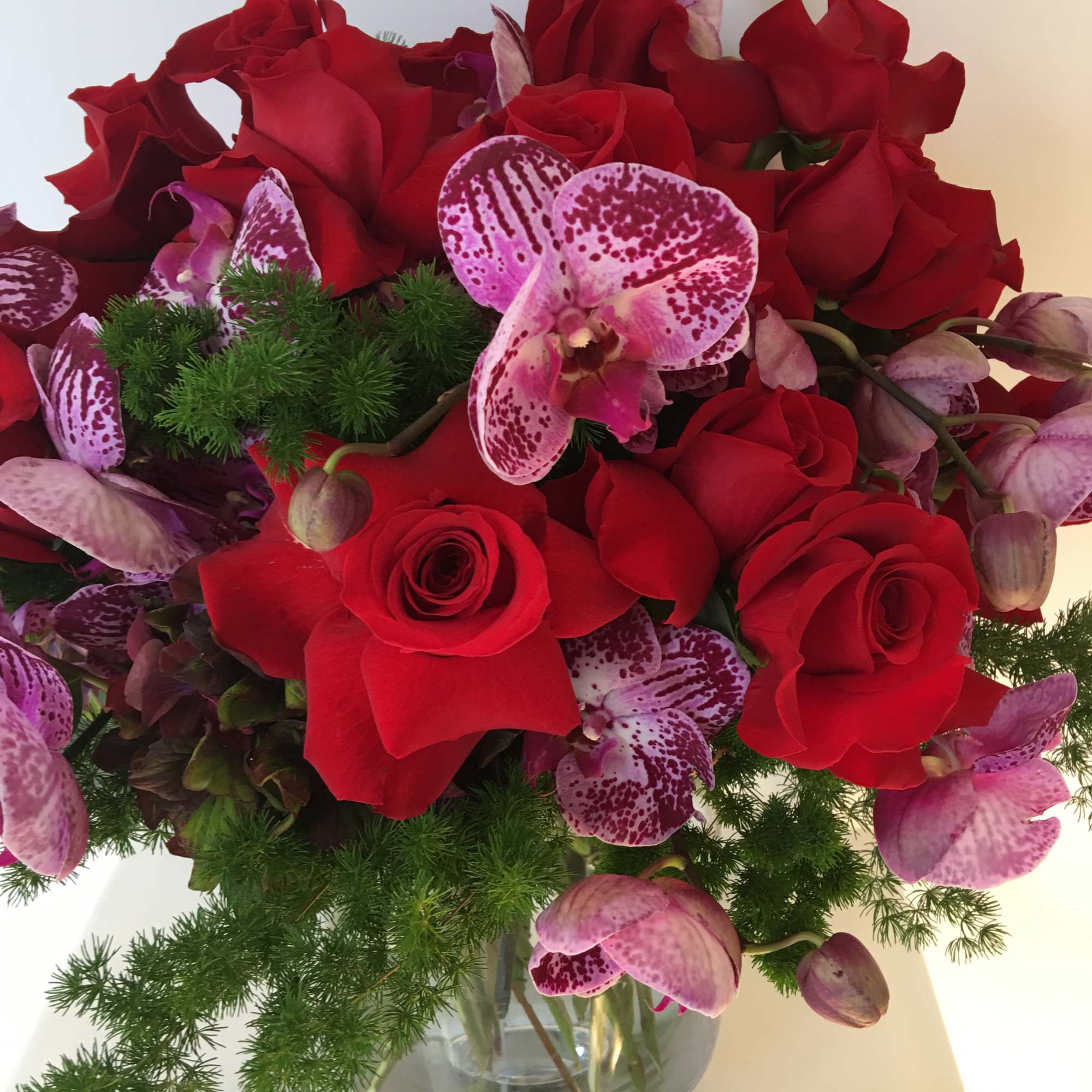 Nice arrangement with red roses and purple orquids nice arrange in a