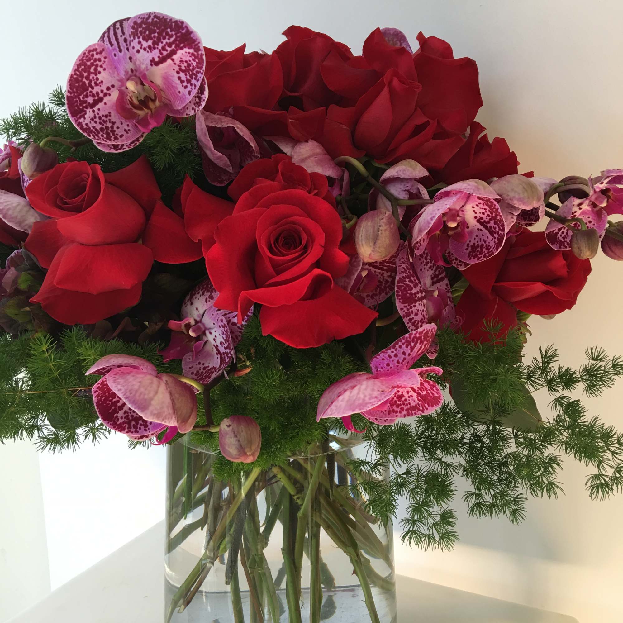 Nice arrangement with red roses and purple orquids nice arrange in a