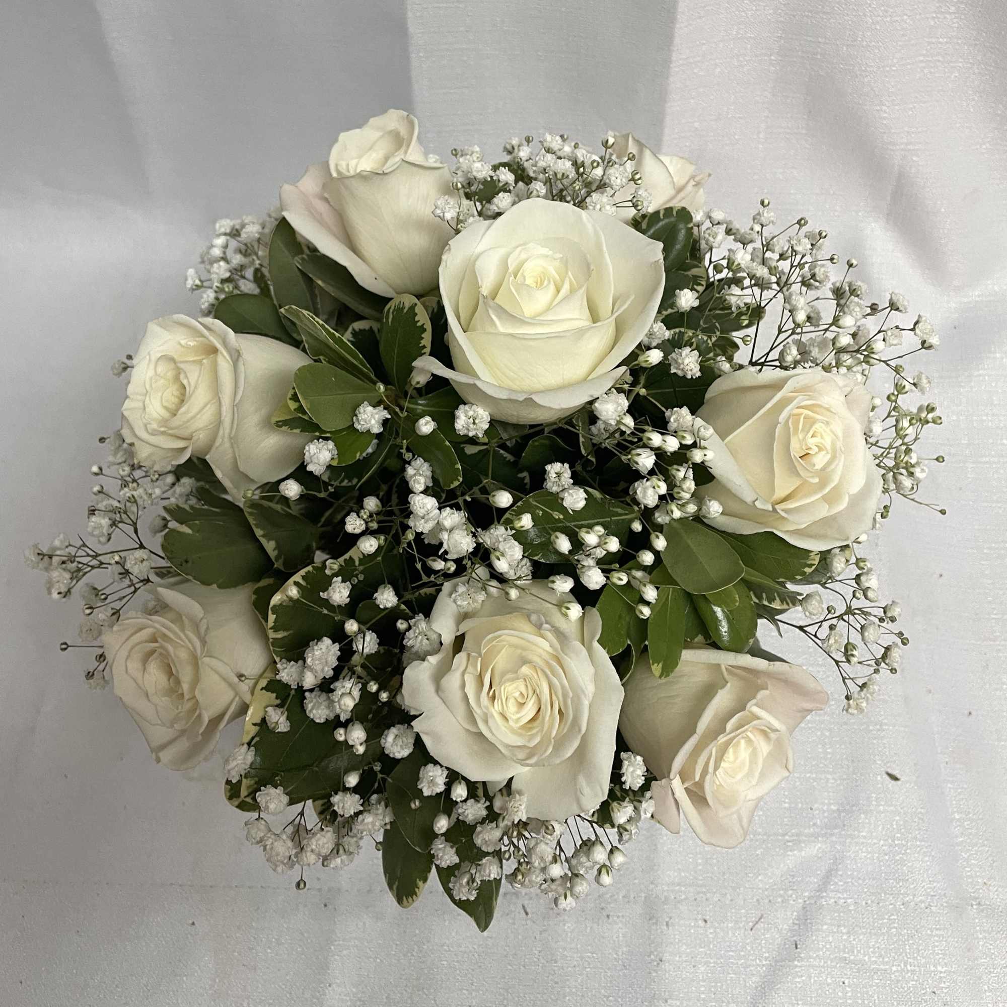 A classic arrangement of white roses and babies breath arranged beautifully with