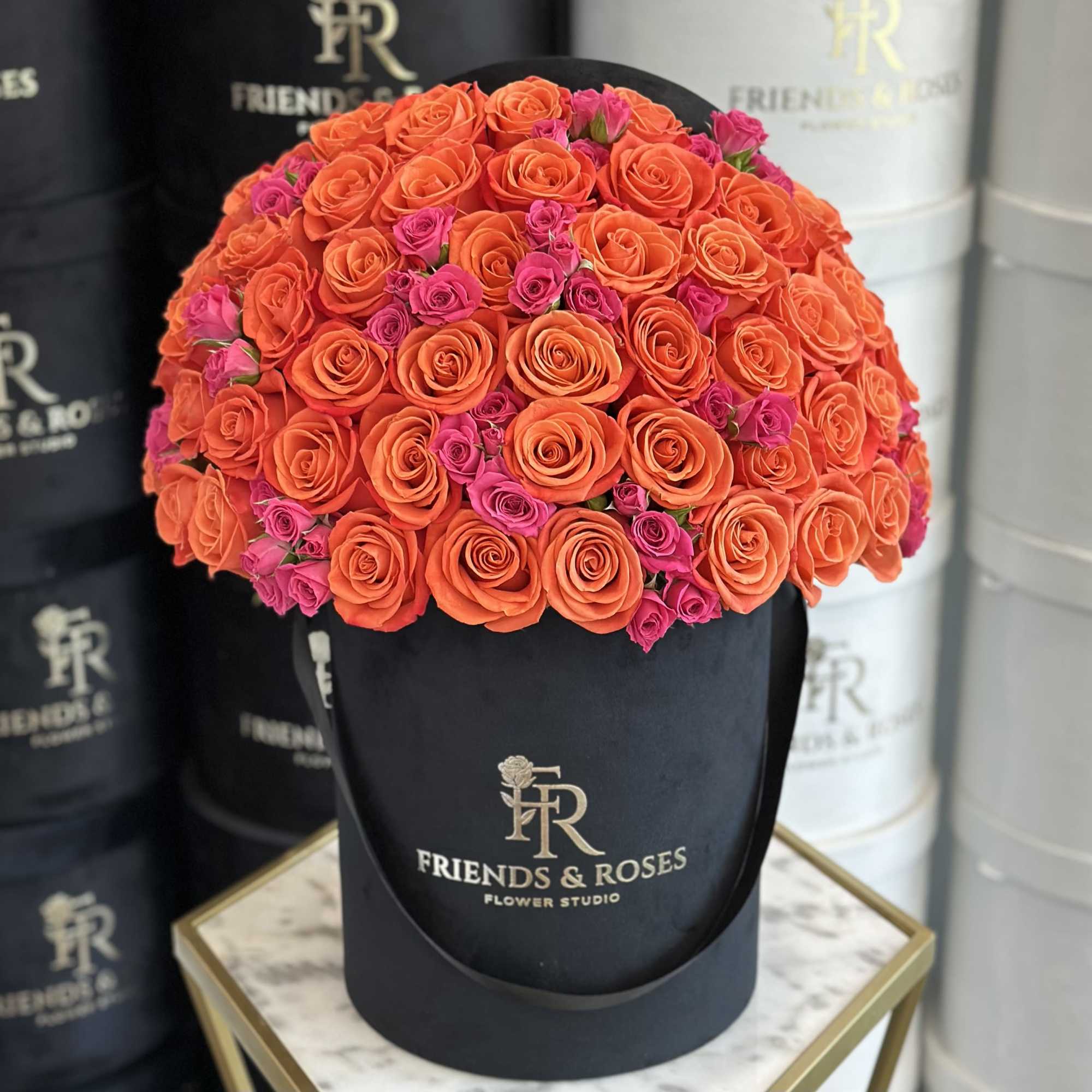 A signature black velvet box adorned with vibrant orange and pink roses.

Standard: