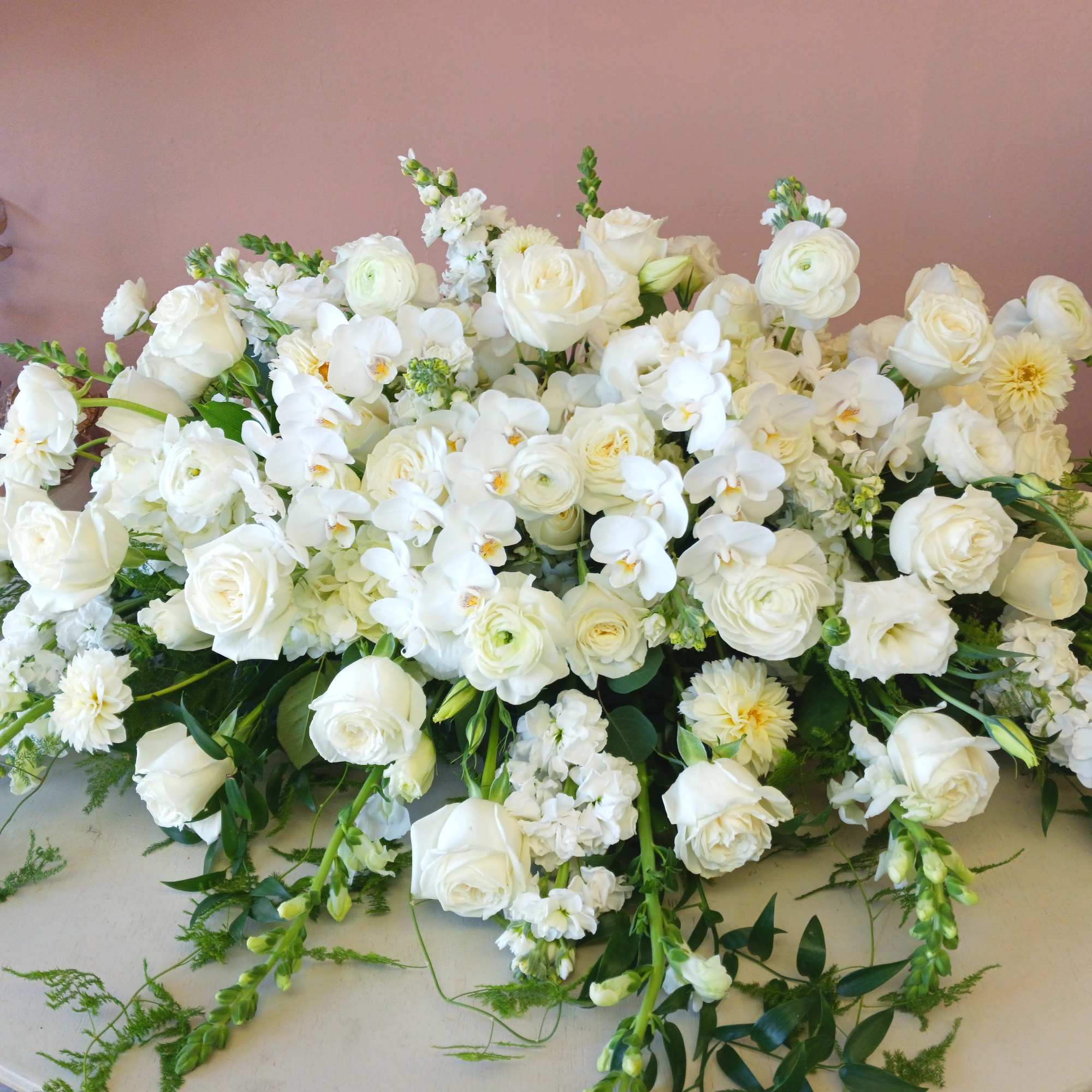 An all white casket spray with all premium flowers. This piece is