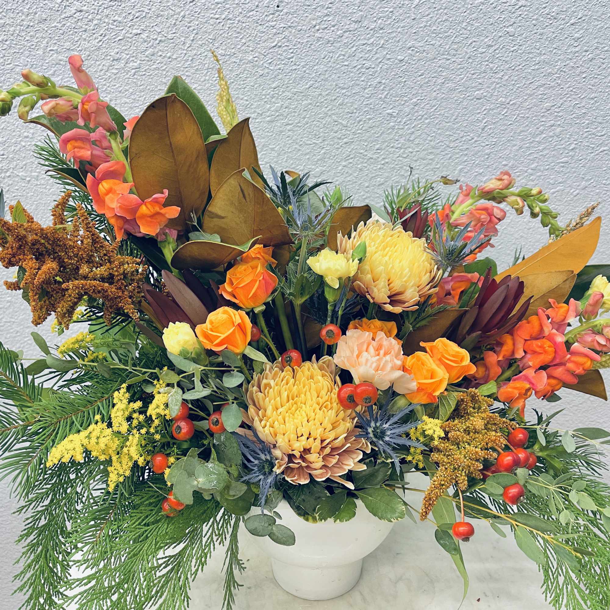 Seasonal flowers paired with seasonal greens in a neutral ceramic pot
*Photo shows
