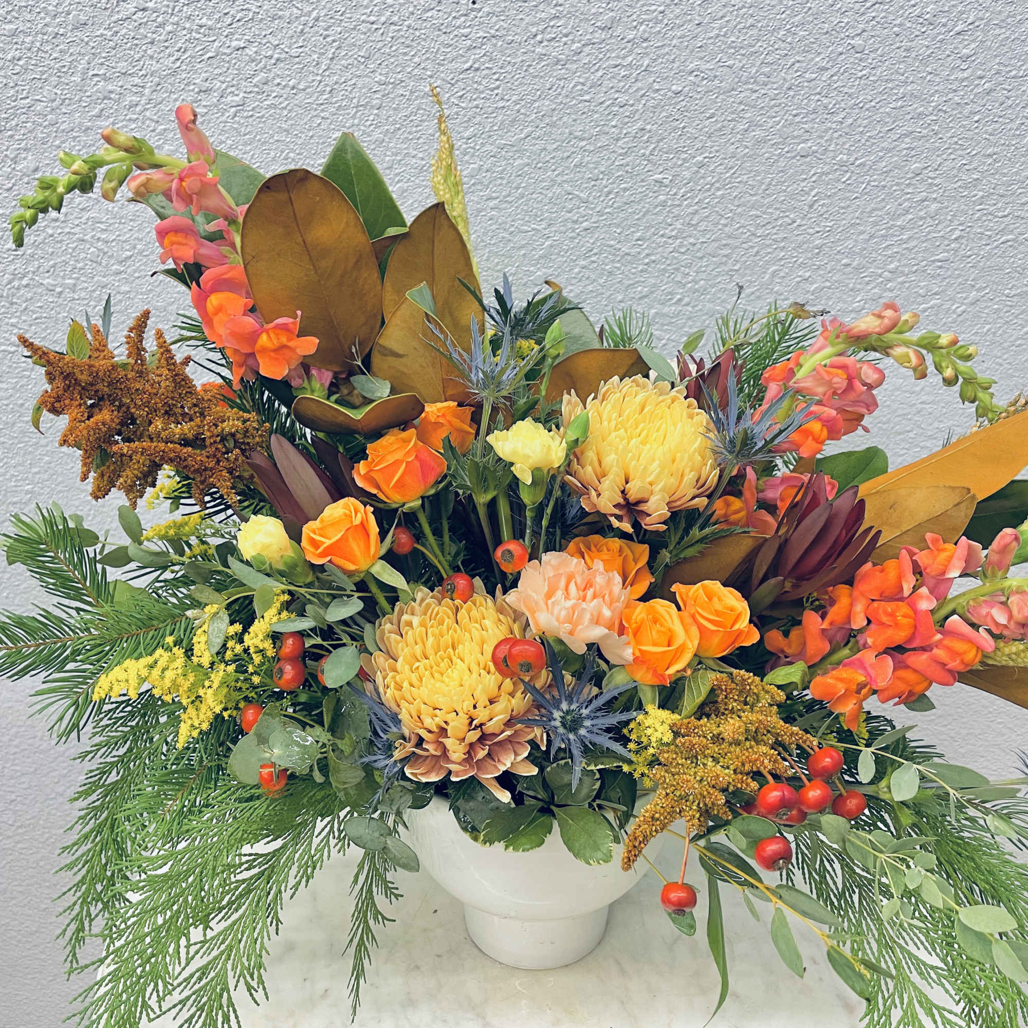 Seasonal flowers paired with seasonal greens in a neutral ceramic pot
*Photo shows