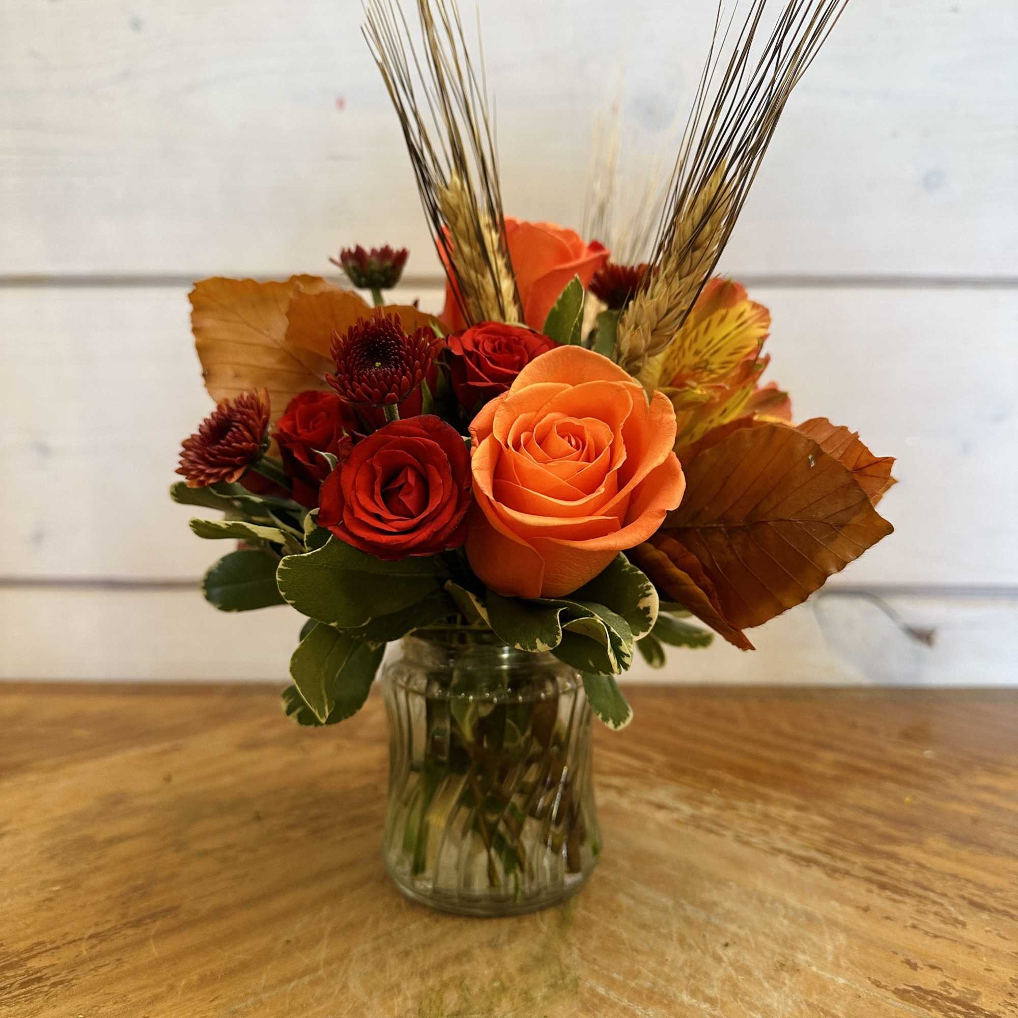 Orange roses, red spray roses, fall chrysanthemums and orange alstroemeria arranged in Orange roses, red spray roses, fall chrysanthemums and orange alstroemeria arranged in