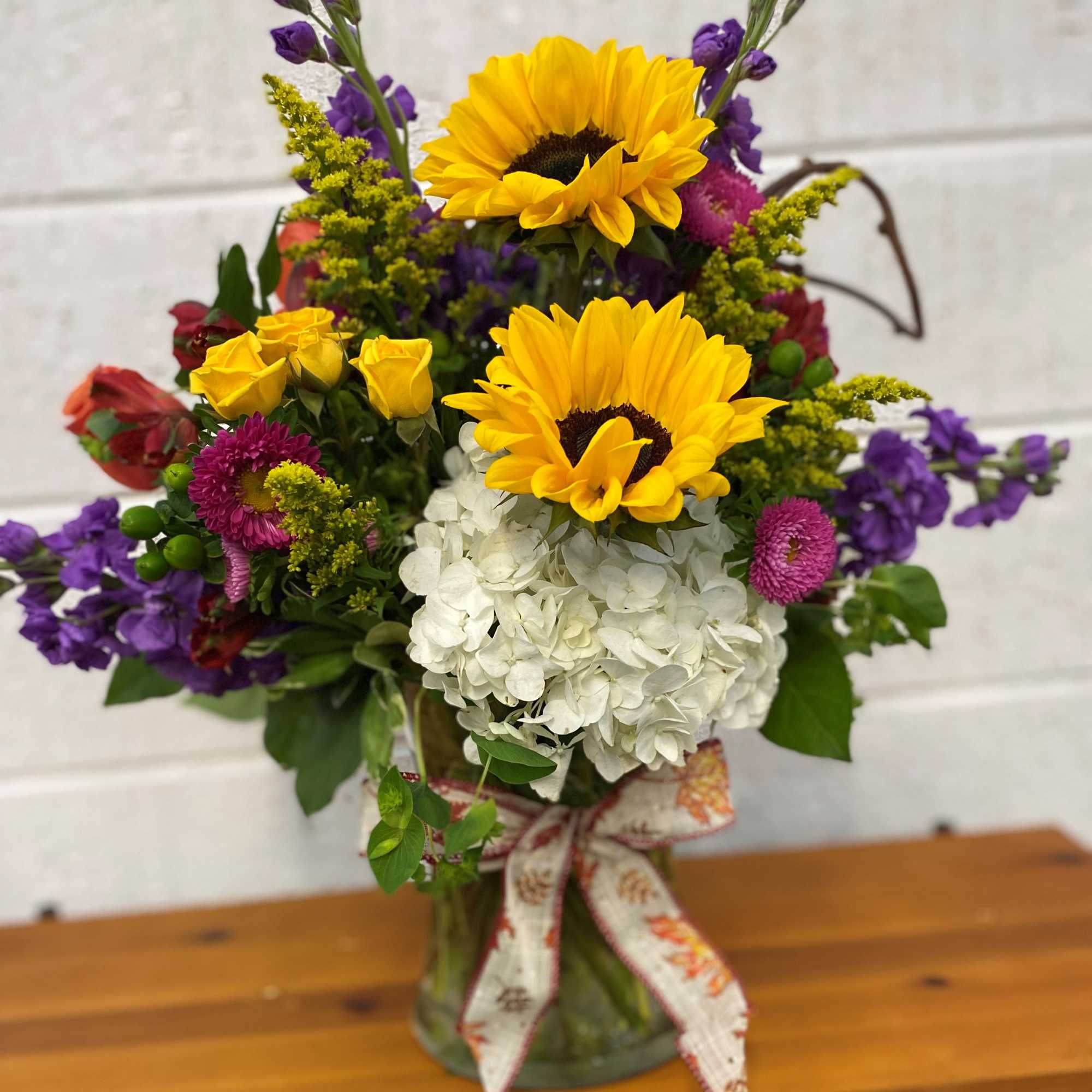 Mix of Fresh Blooms designed in a large gathering vase accented with