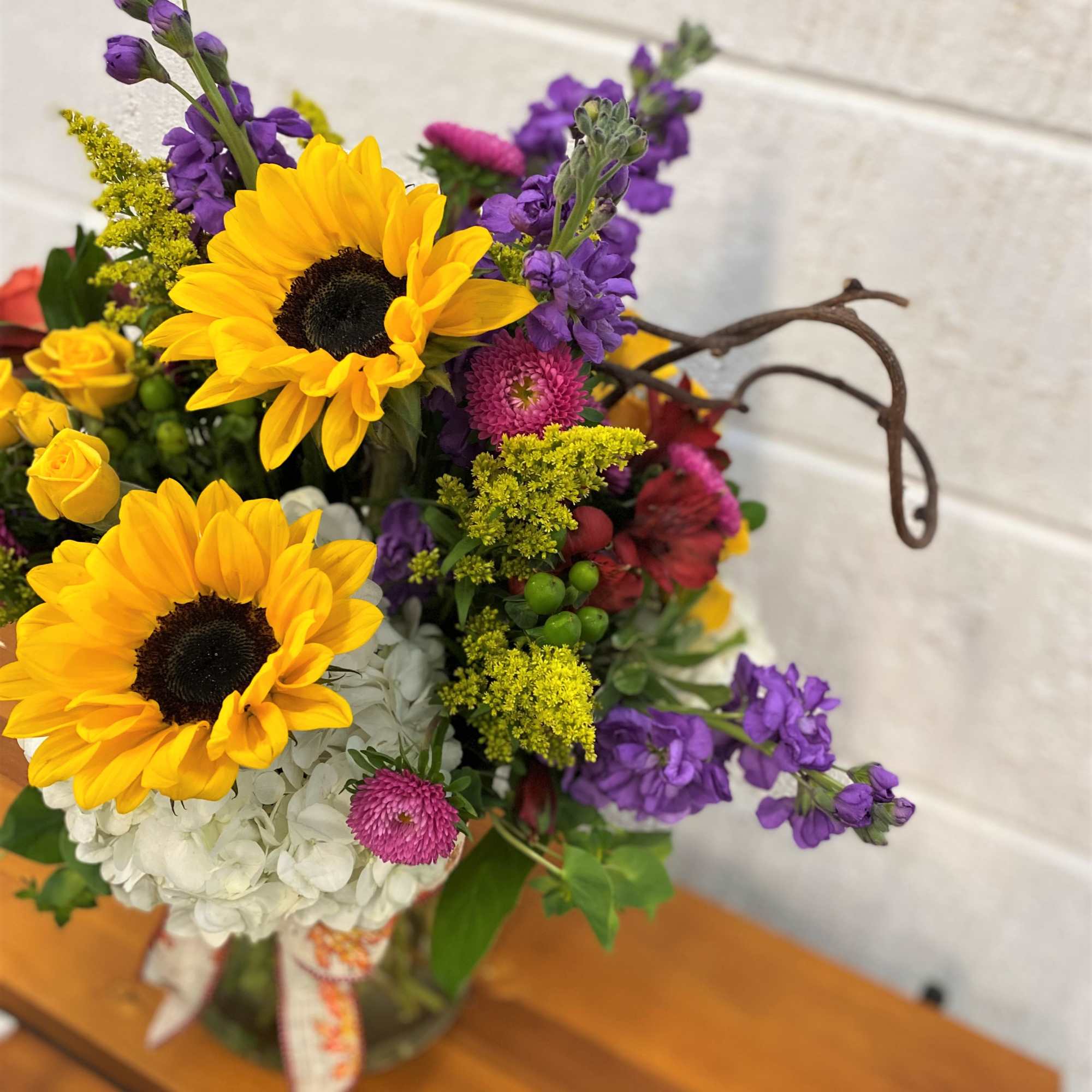 Mix of Fresh Blooms designed in a large gathering vase accented with