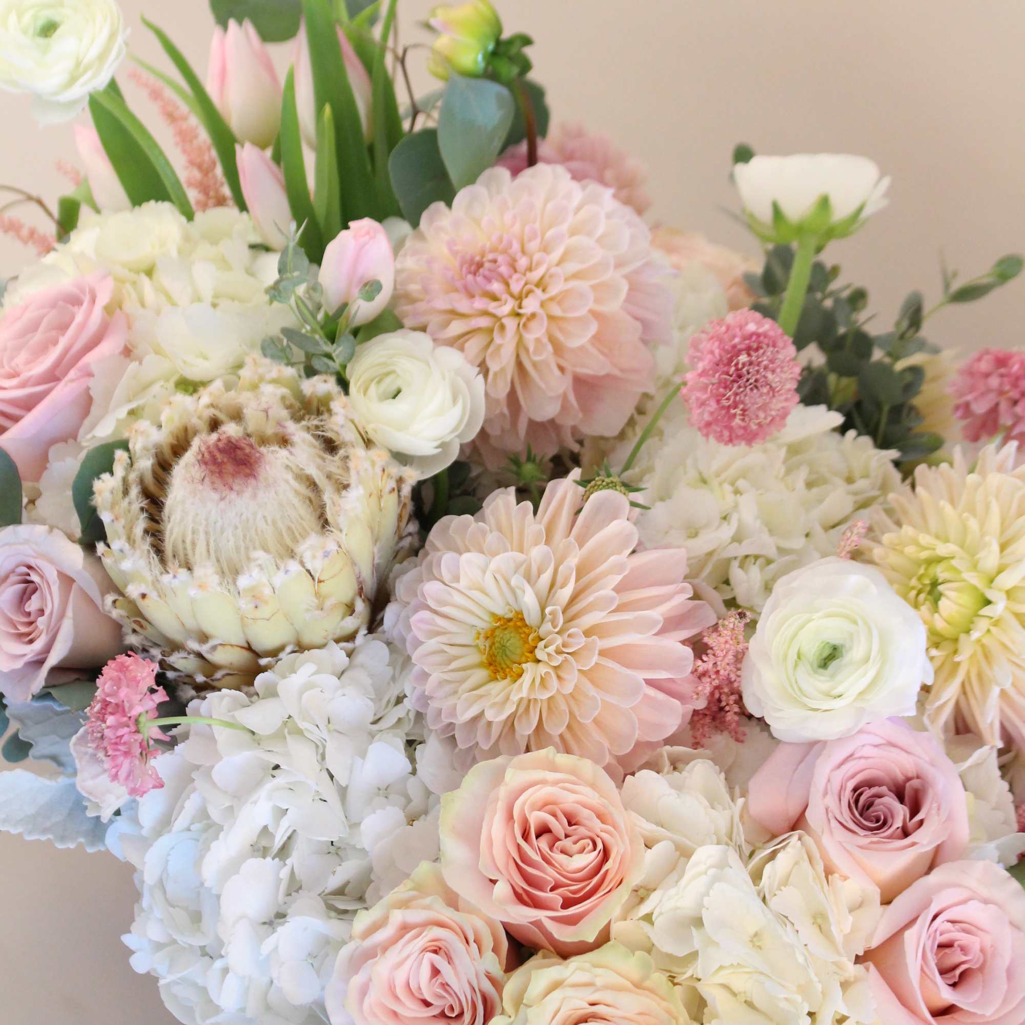 A very lush arrangement of blush, pinks and white in a ceramic