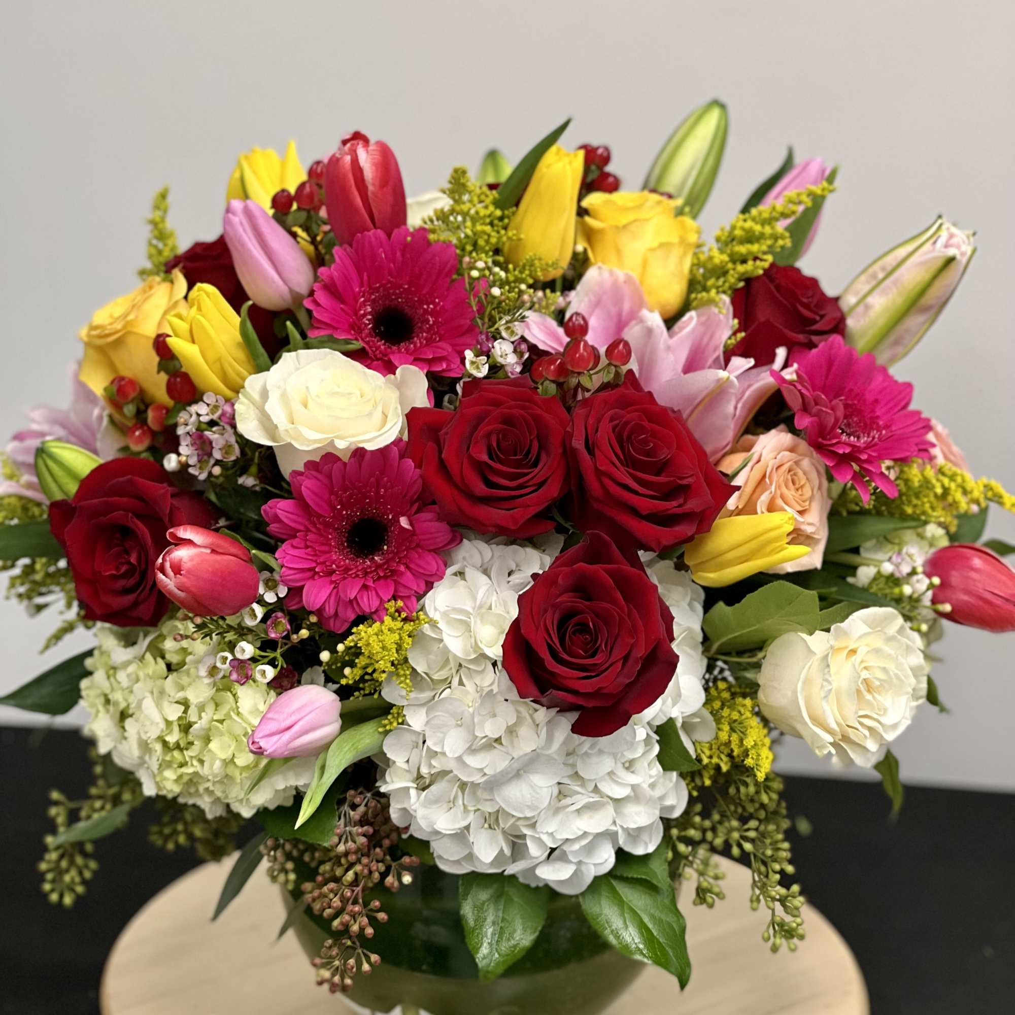 This garden style arrangement includes gerbera daisies, roses, tulips, lilies, and seasonal This garden style arrangement includes gerbera daisies, roses, tulips, lilies, and seasonal