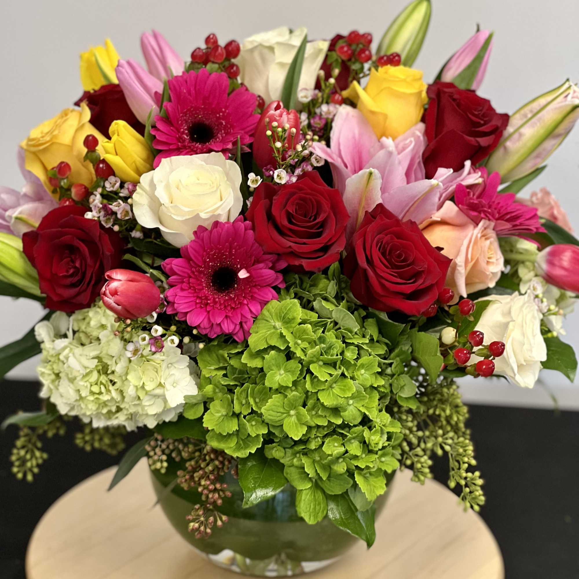 This garden style arrangement includes gerbera daisies, roses, tulips, lilies, and seasonal This garden style arrangement includes gerbera daisies, roses, tulips, lilies, and seasonal