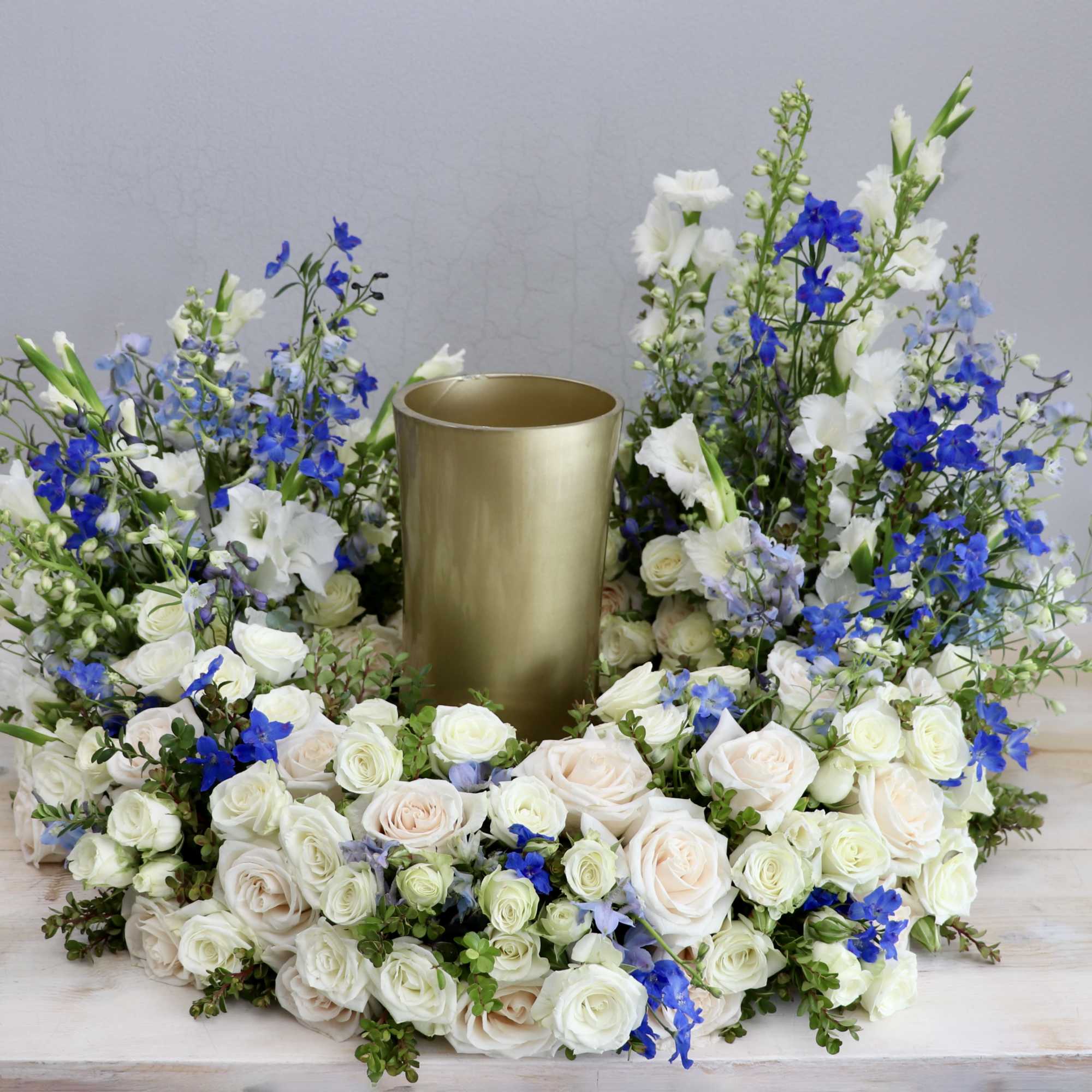 This urn tribute wreath includes a mix of flowers, roses, and seasonal