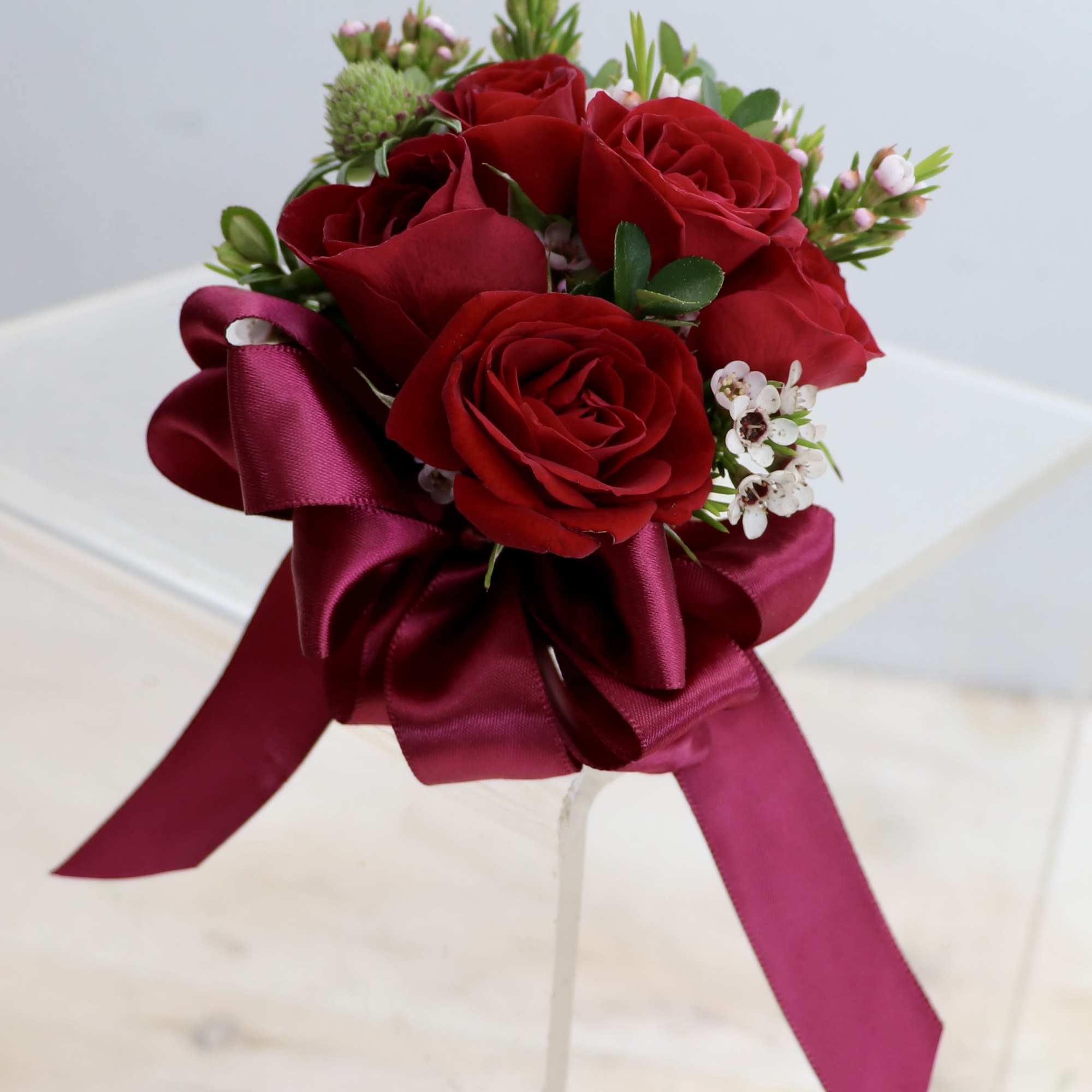 Orchid or rose boutonniere include seasonal greens, and a ribbon in the