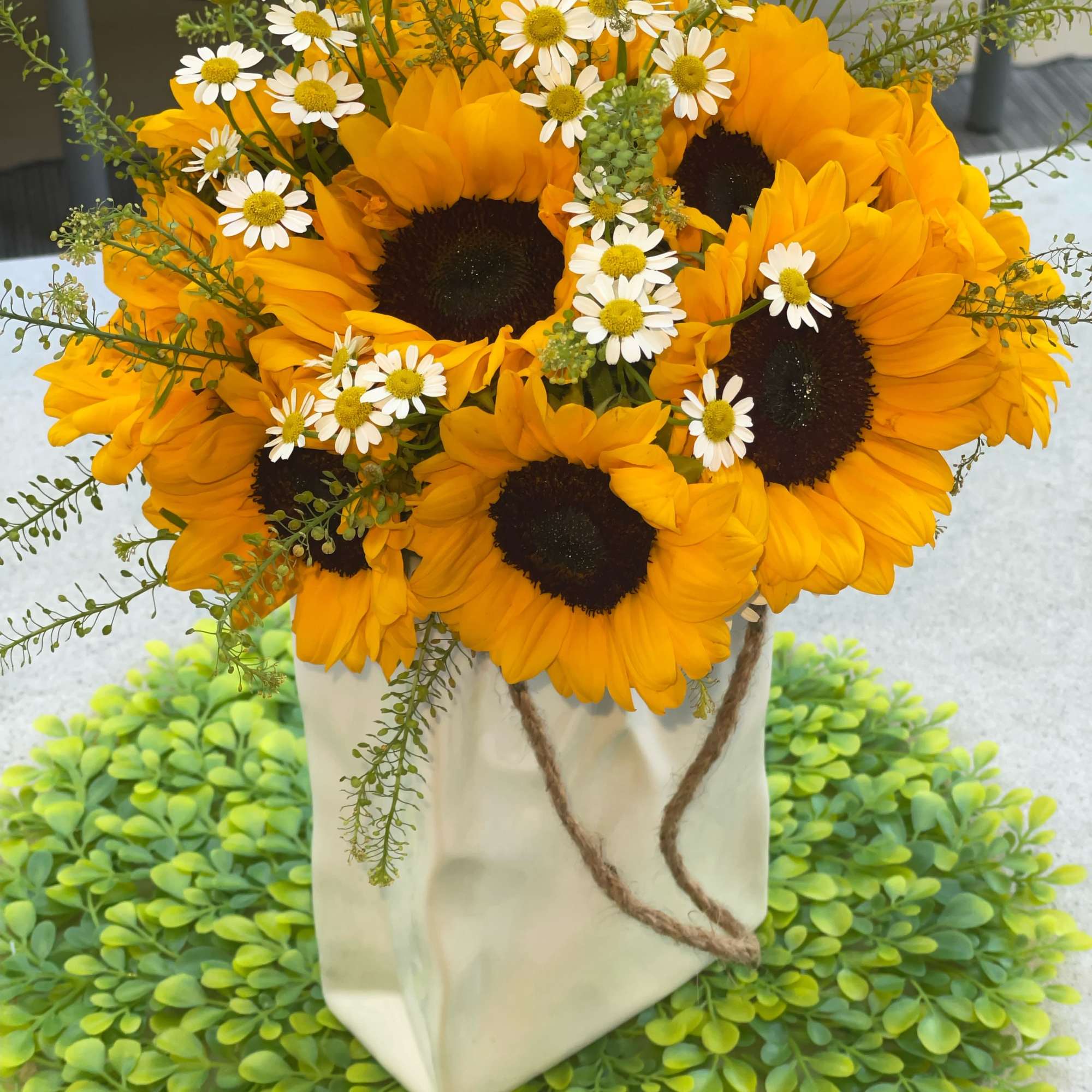 This stunning floral arrangement features a beautiful blend of sunflowers and daisies.