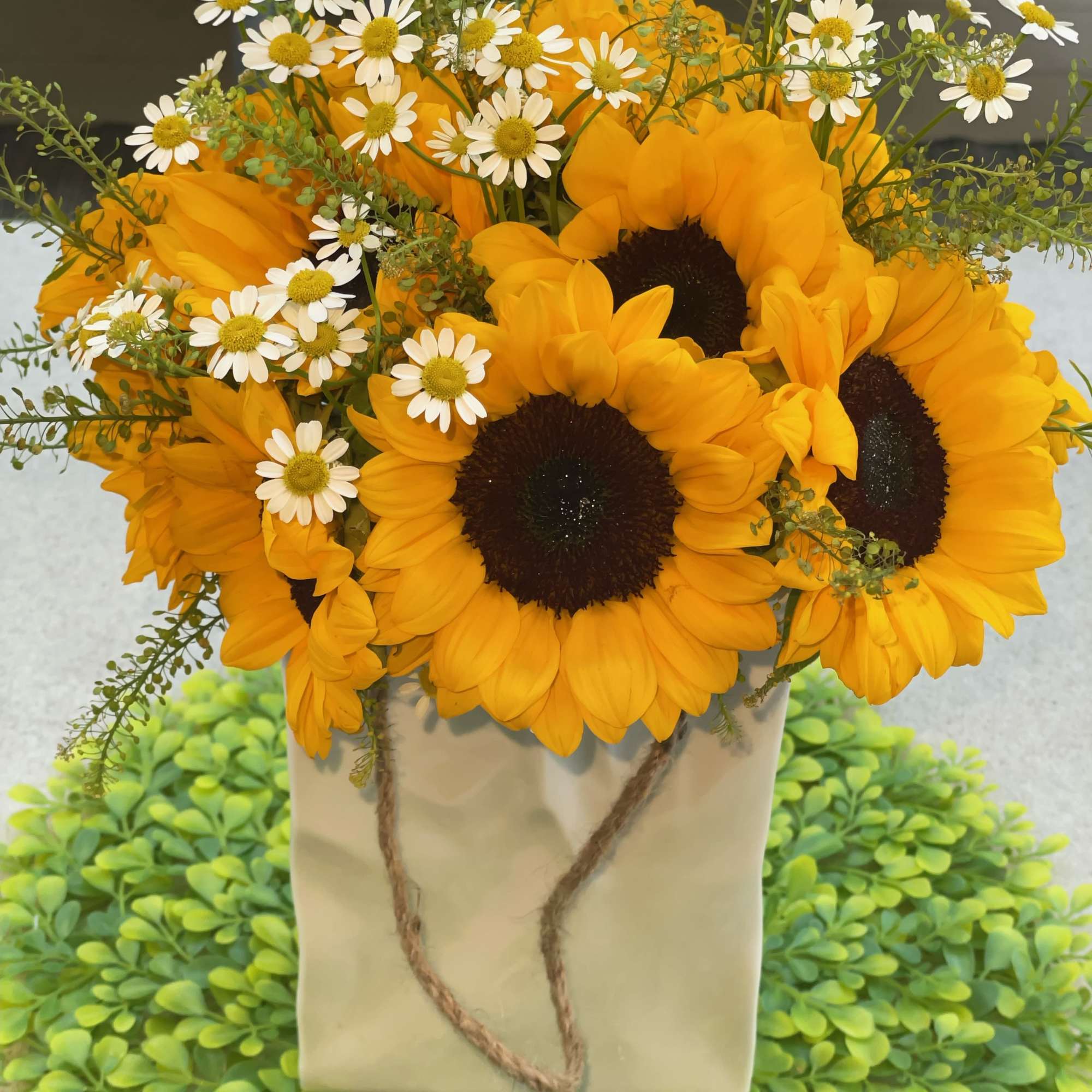This stunning floral arrangement features a beautiful blend of sunflowers and daisies.