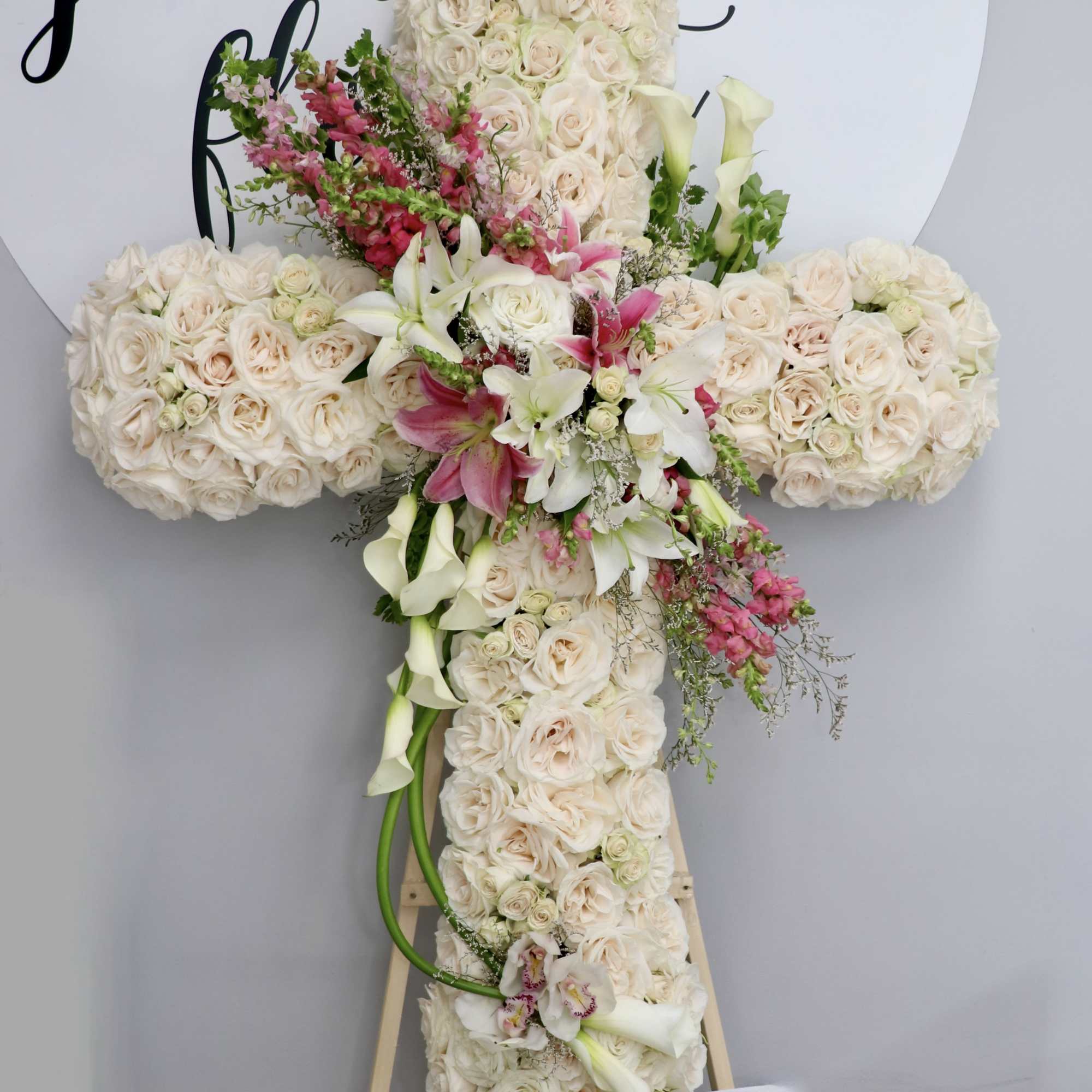 This cross is made with white roses and accented with a pink