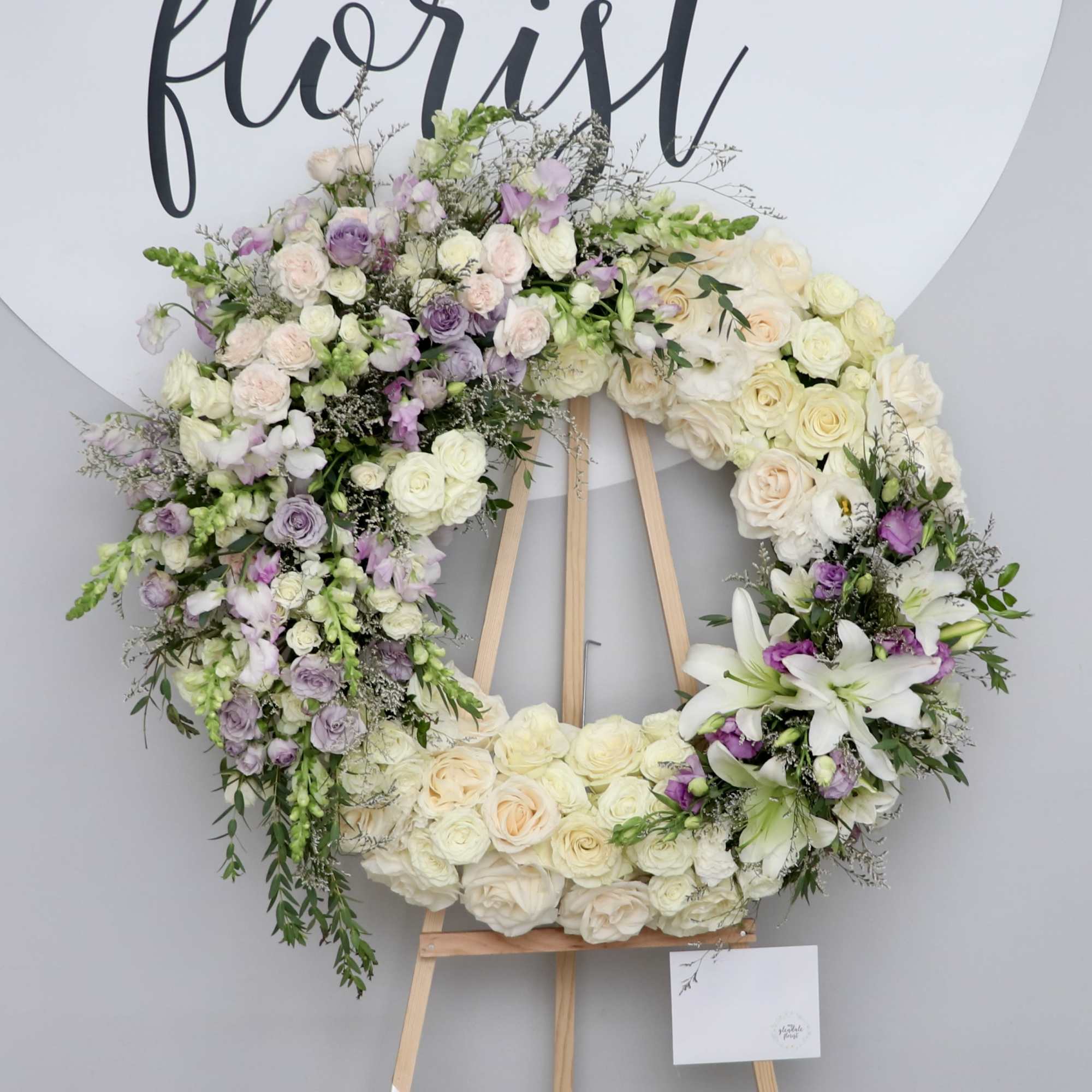 This beautiful sympathy wreath is made with white roses and accented with