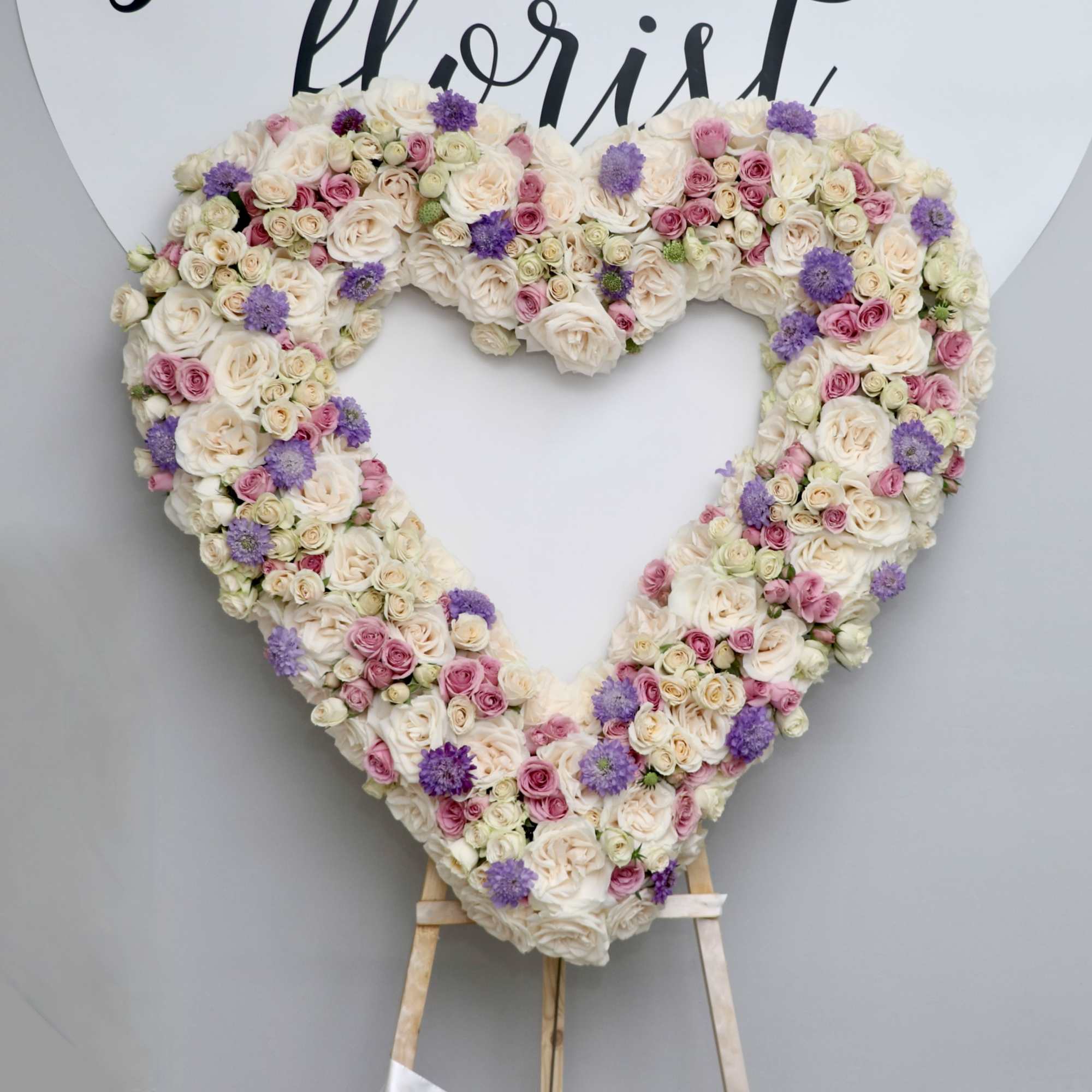 This heart wreath is made with white roses and accented with pink