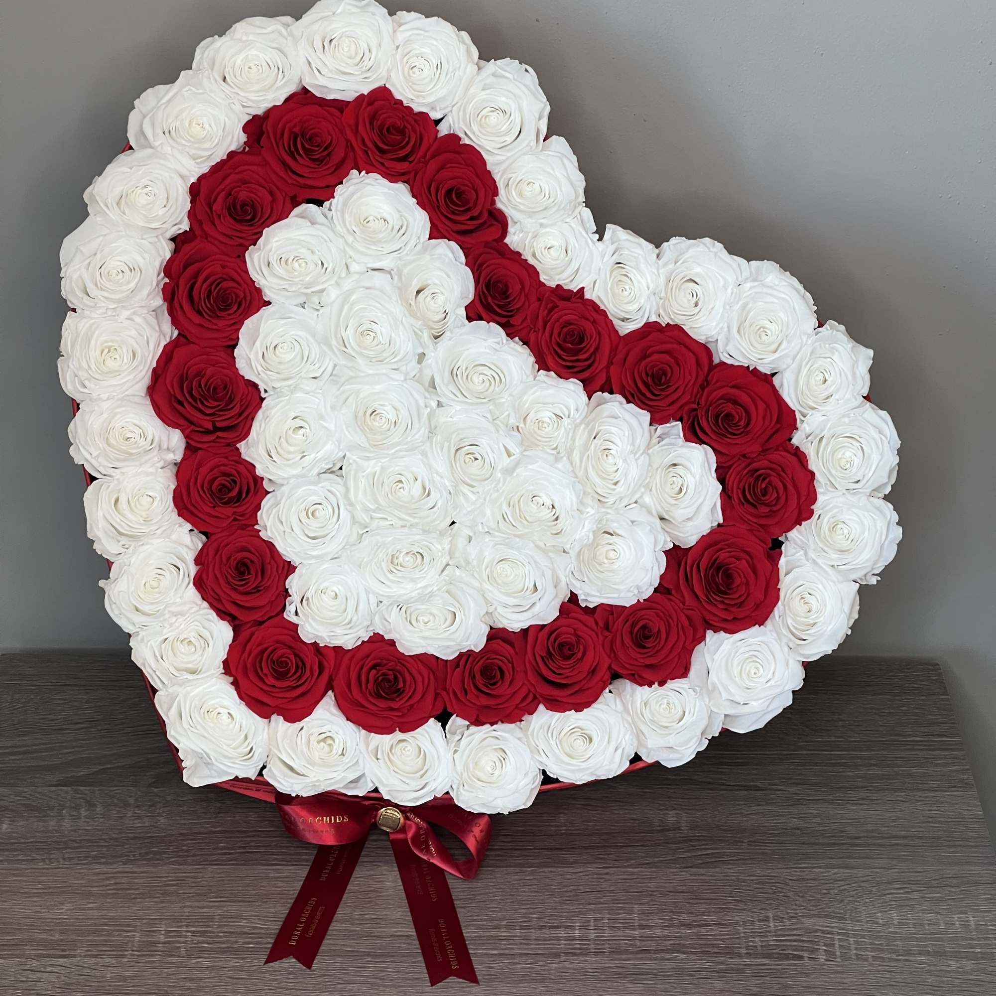 This breathtaking heart-shaped preserved arrangement features a striking pattern of white roses This breathtaking heart-shaped preserved arrangement features a striking pattern of white roses
