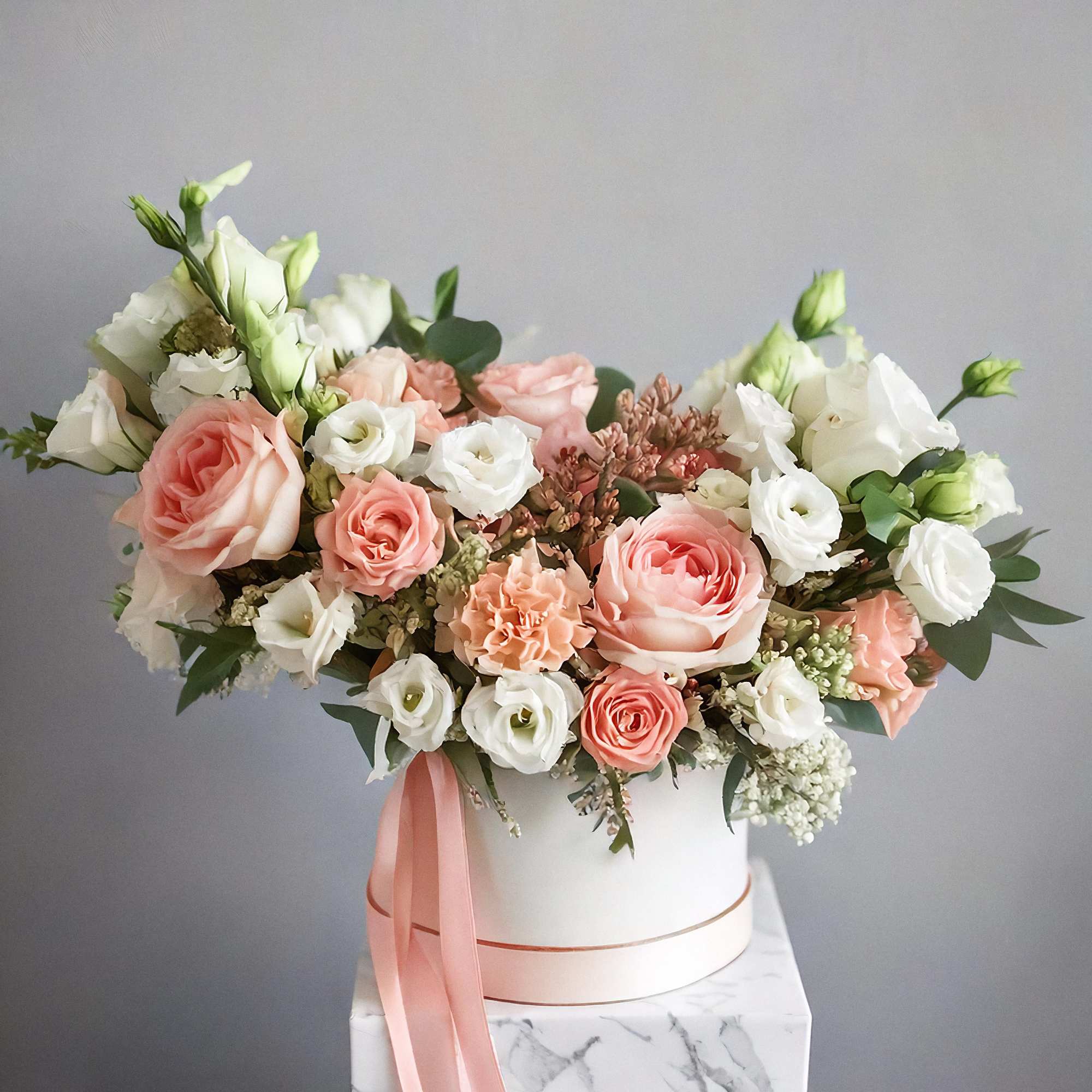 The arrangement features a stunning mix of flowers, including white and peach
