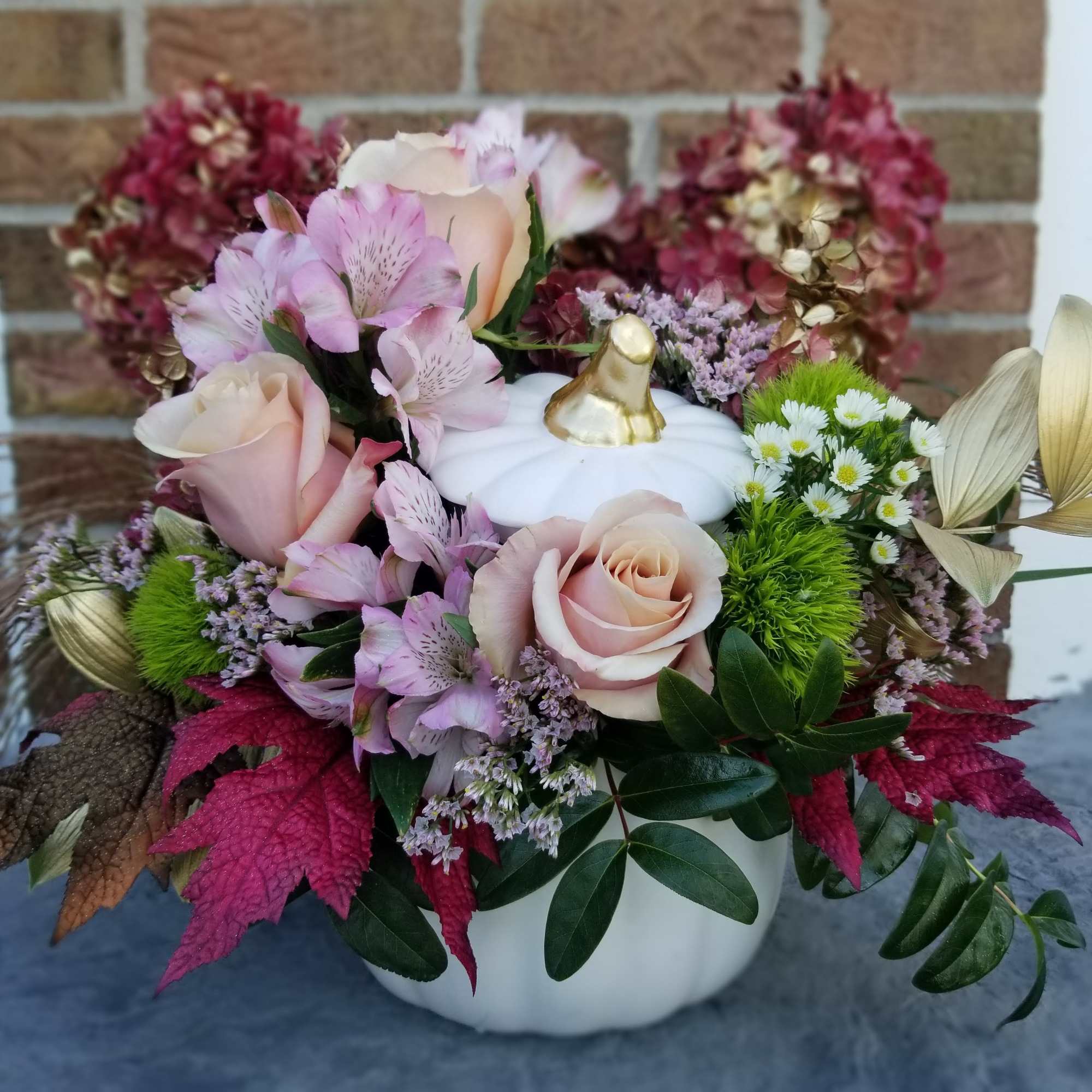 Designed in a white ceramic pumpkin.  Flowers chosen for this royal