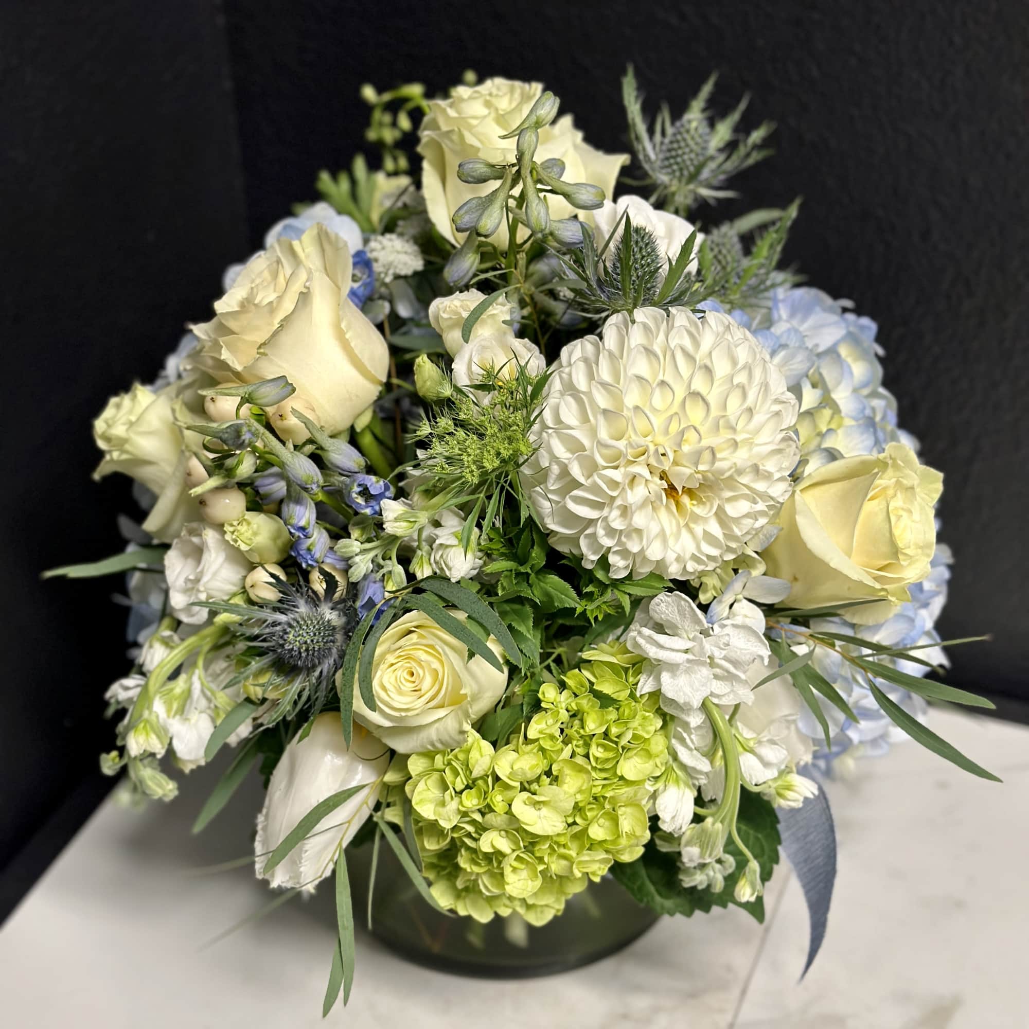 An elegant seasonal garden mix in creamy whites, blues and greens. Arranged