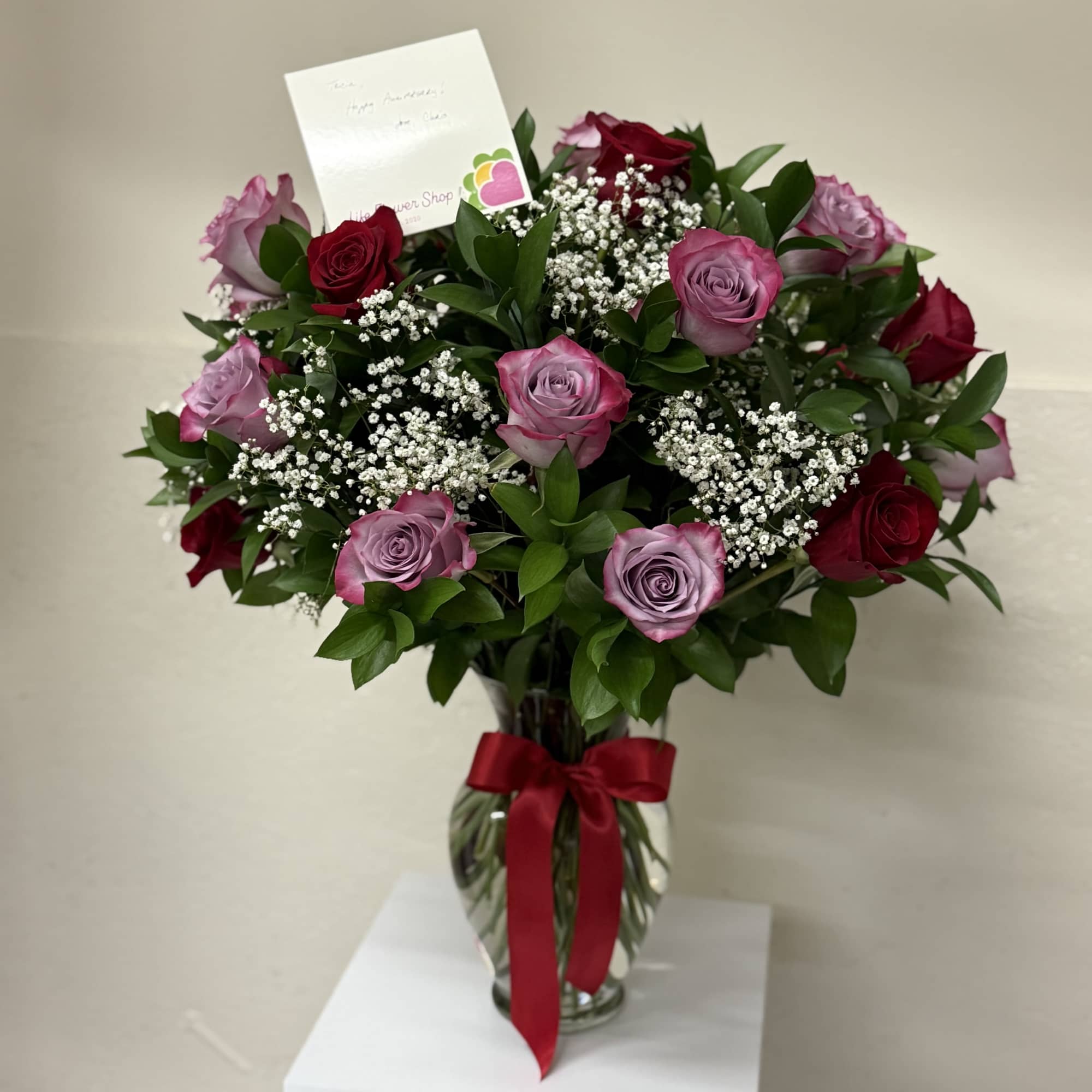 A stunning arrangement of 24 mixed roses in vibrant colors, beautifully presented A stunning arrangement of 24 mixed roses in vibrant colors, beautifully presented