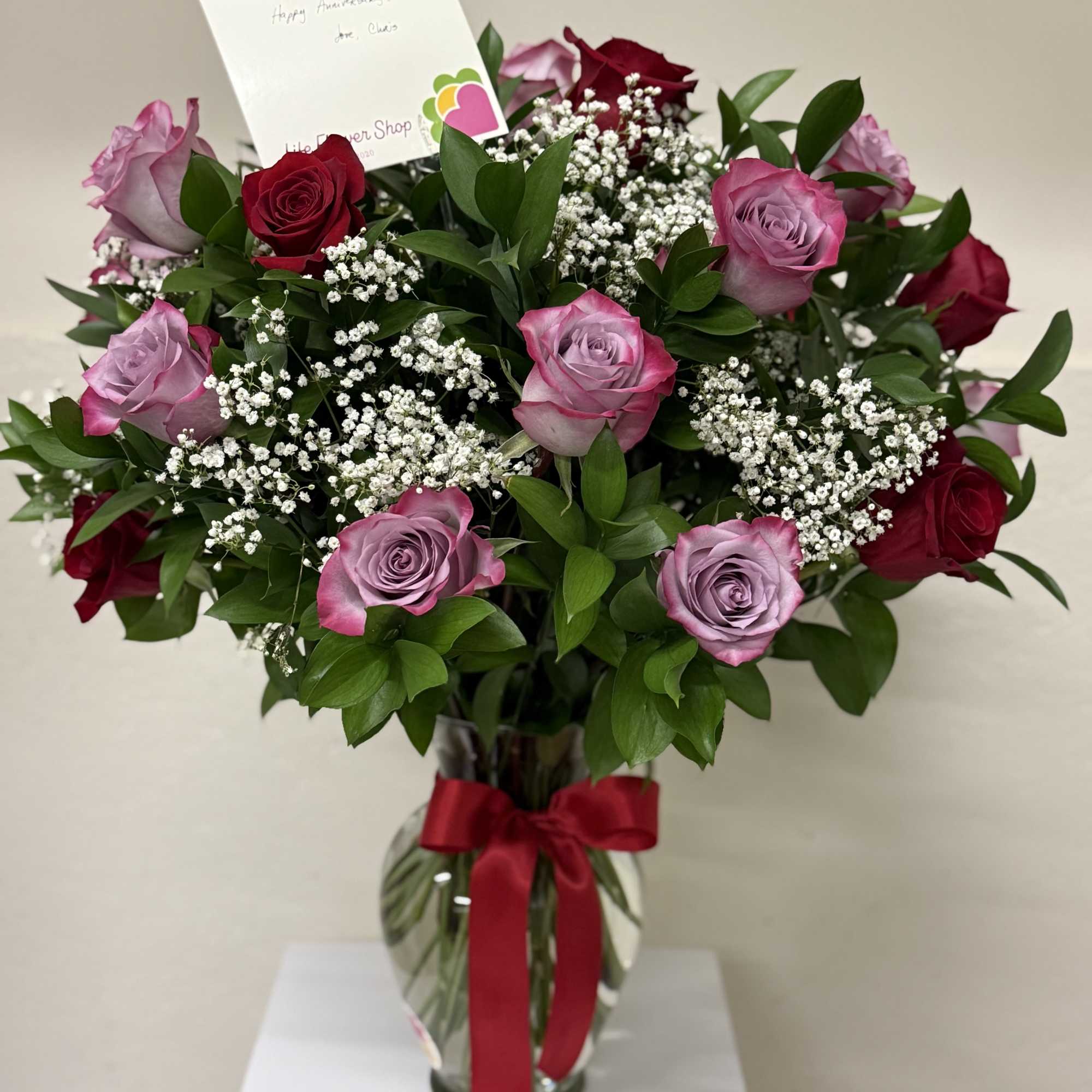A stunning arrangement of 24 mixed roses in vibrant colors, beautifully presented A stunning arrangement of 24 mixed roses in vibrant colors, beautifully presented