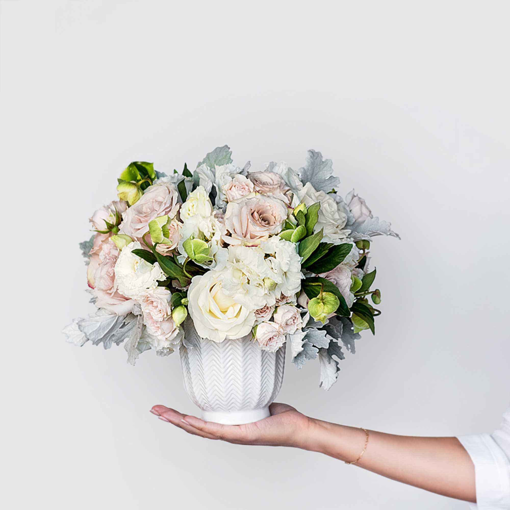 The Blush Bliss arrangement pairs soft blush roses, white hydrangeas, lisianthus, and