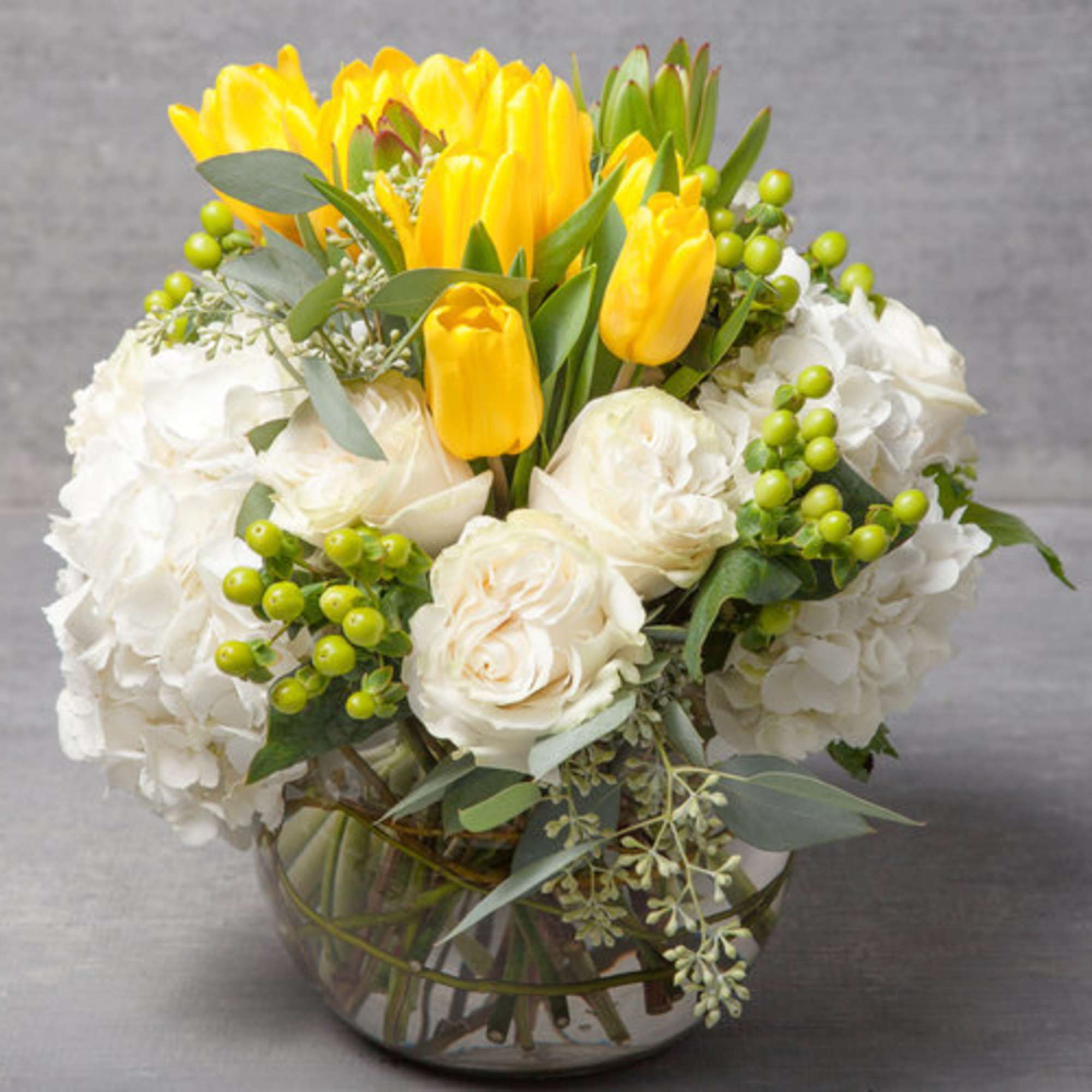 A fresh and happy arrangement of golden yellow tulips, linen white blossoms